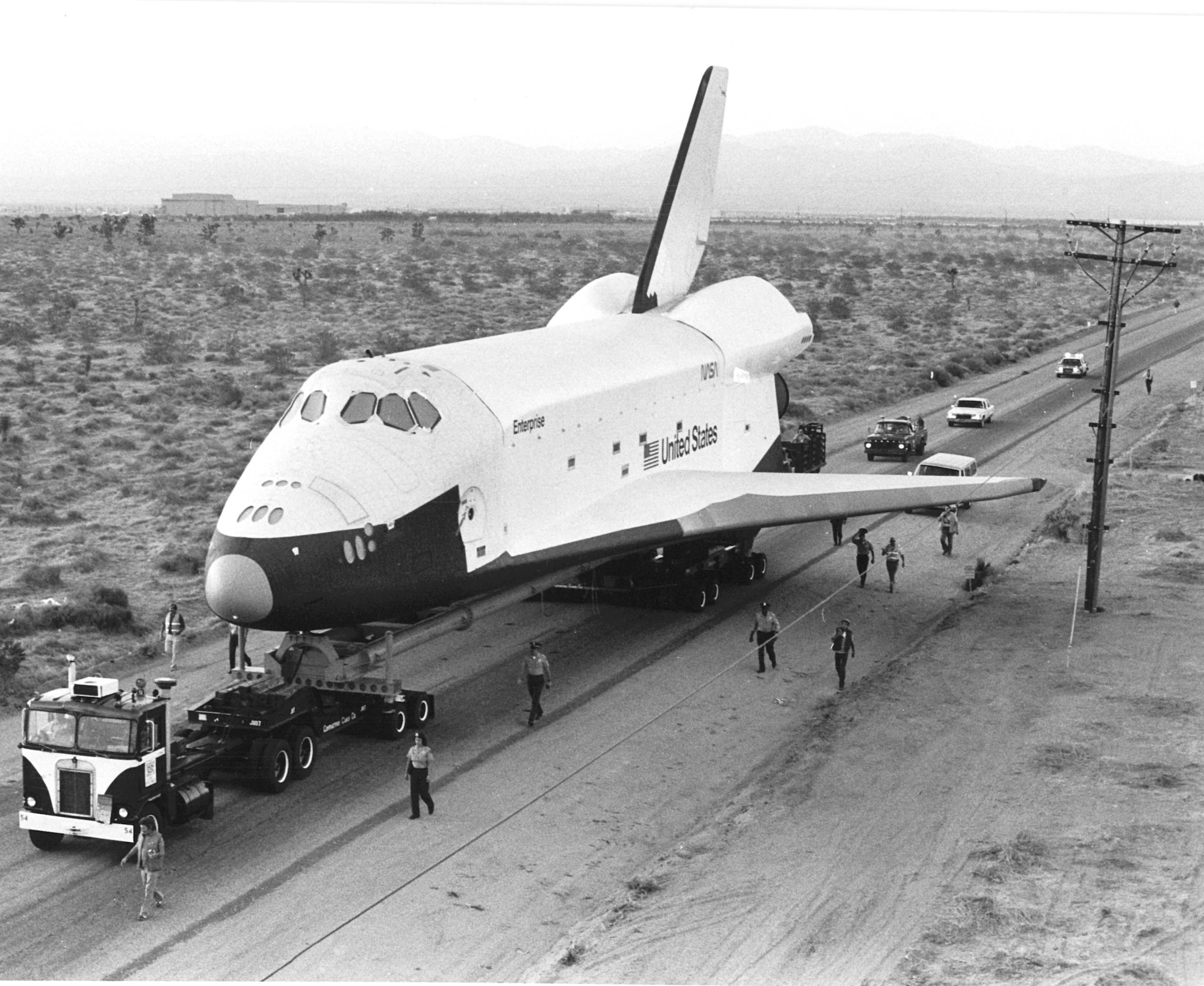 The first Space Shuttle orbiter, Enterprise, arrived at Edwards AFB on January 31, 1977.  It had been moved via road at 3 mph from Rockwell International’s assembly facility at Palmdale aboard a 90-wheel transporter.  The unpowered version of the Shuttle was housed at Dryden Flight Research Center in preparation for a series of ground, captive- and free-flight tests prior to the space launch program. (Courtesy Photo) 