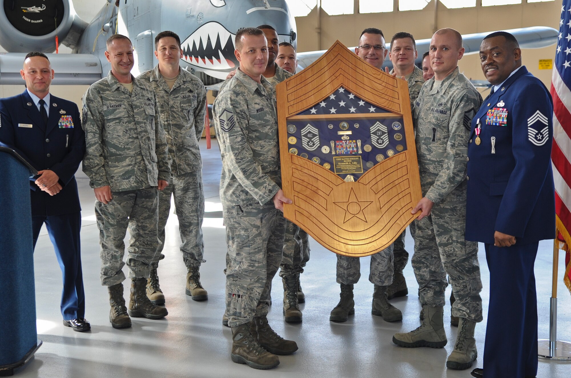 U.S. Air Force Chief Master Sgt. Kenneth Lilly, 23rd Wing weapons manager, is presented with a shadow box by Master Sgt. Dennis Wisser, 75th Aircraft Maintenance Unit section chief, Master Sgt. Scotty Stanton, 41st Helicopter Maintenance Unit Weapons flight chief, and other various squadron chiefs during his retirement ceremony at Moody Air Force Base, Ga., Dec. 19, 2011. Lilly spent 30 years in the Air Force achieving the rank that only one percent of the total enlisted corps ever will. (U.S. Air Force photo by Airman 1st Class Olivia Dominique/Released)