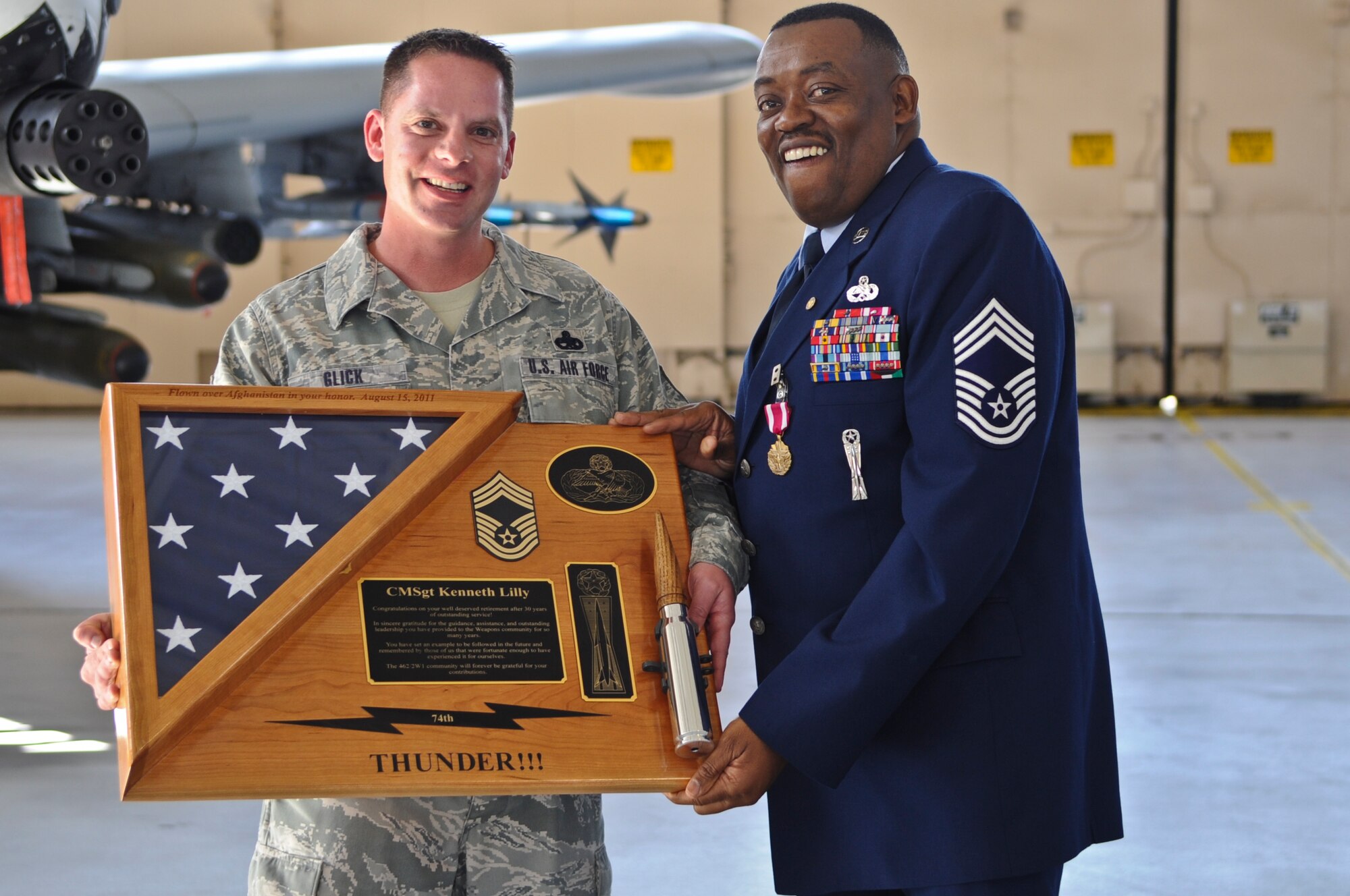 U.S. Air Force Chief Master Sgt. Kenneth Lilly, 23rd Wing weapons manager, is presented with a plaque of recognition from Master Sgt. Steven Glick, 74th Aircraft Maintenance Unit section chief, during his retirement ceremony held at Moody Air Force Base, Ga., Dec. 19, 2011. Throughout his 30 year career, Lilly has worked with several different units and with various weapons systems. (U.S. Air Force photo by Airman 1st Class Olivia Dominique/Released)