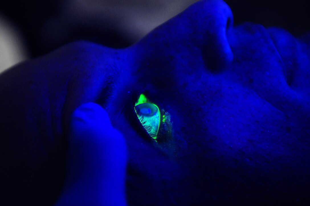 A black light illuminates U.S. Navy Petty Officer 1st Class Alfonso Camacho's eyes after he received fluorescein drops during an exam in the medical department aboard the USS Carl Vinson under way in the Pacific Ocean, Dec. 17, 2011. Camacho is a hospital corpsman. Fluorescein is used to detect problems on an eye's cornea.