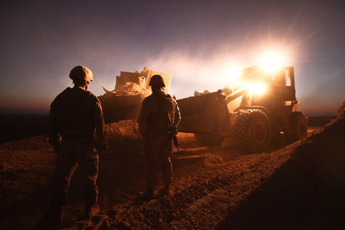Sgt. Cody Palfreyman (left) and Staff Sgt. Ty Horn, both combat engineers with Alpha Company, 9th Engineer Support Battalion, guide a bulldozer as it moves the berm surrounding a guard post at Firebase Saenz, Helmand province, Dec. 14. FB Saenz is the first of several patrol bases being demilitarized by the Marines of 9th ESB throughout the month of December.