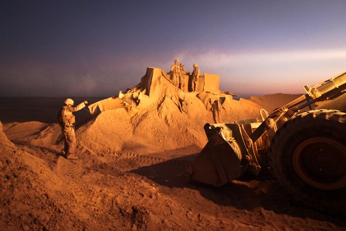 Sgt. Cody Palfreyman, a combat engineer with Alpha Company, 9th Engineer Support Battalion, and a native of West Valley, Utah, guides a bulldozer as it moves the berm surrounding a guard post at Firebase Saenz, Helmand province, Dec. 14. FB Saenz is the first of several patrol bases being demilitarized by the Marines of 9th ESB throughout the month of December.