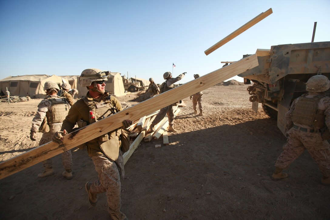 Marines with Alpha Company, 9th Engineer Support Battalion throw pieces of wood from a tent into the back of a dump truck at Support Battalion, guide a bulldozer as it moves the berm surrounding a guard post at Firebase Saenz, Helmand province, Dec. 15. FB Saenz is the first of several patrol bases being demilitarized by the Marines of 9th ESB throughout the month of December.