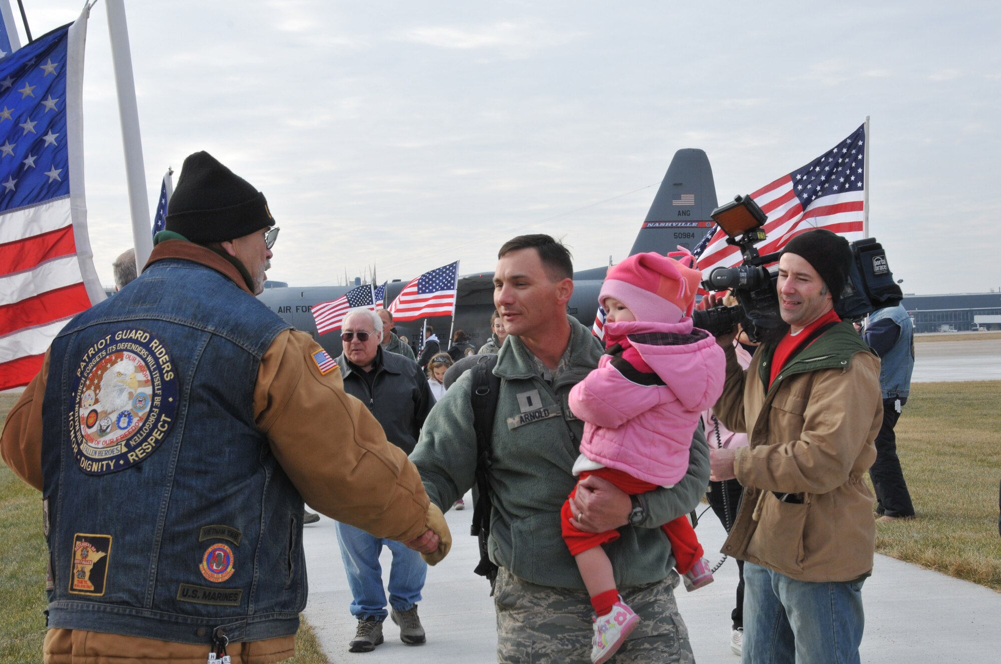 Airmen and family members walk through a line of Patriot Guard Riders in front of the 133rd Airlift Wing operations building on Dec. 21, 2011. The airmen returned from six months in Kuwait supporting Operation New Dawn and are from the 133rd Civil Engineer Squadron of the Minnesota Air National Guard. They have been working with buildings and utilities at bases in Kuwait as the U. S. military pulled out of Iraq. USAF photo by Senior Airman Kennith Veillon