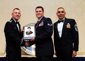 Col. Richard McComb and Chief Master Sgt. Jose LugoSantiago present the John L. Levitow Award to Senior Airman Johnathan Baxley during the Airman Leadership School Class graduation at Joint Base Charleston - Air Base Dec. 15. The award is presented to the student who displays exemplary excellence as both  a leader and a scholar. McComb is the JB Charleston commander and LugoSantiago is the 628th Air Base Wing command chief. Baxley is an explosive ordnance disposal journeyman assigned to the 628th Civil Engineer Squadron. (U.S. Air Force photo/Staff Sgt. Katie Gieratz) 
