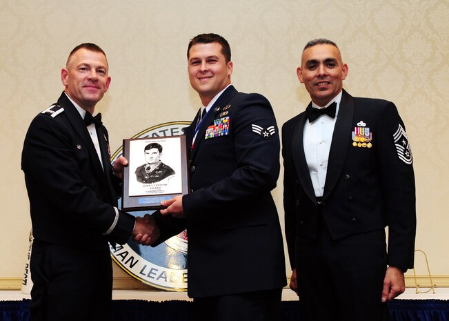 Col. Richard McComb and Chief Master Sgt. Jose LugoSantiago present the John L. Levitow Award to Senior Airman Johnathan Baxley during the Airman Leadership School Class graduation at Joint Base Charleston - Air Base Dec. 15. The award is presented to the student who displays exemplary excellence as both  a leader and a scholar. McComb is the JB Charleston commander and LugoSantiago is the 628th Air Base Wing command chief. Baxley is an explosive ordnance disposal journeyman assigned to the 628th Civil Engineer Squadron. (U.S. Air Force photo/Staff Sgt. Katie Gieratz) 
