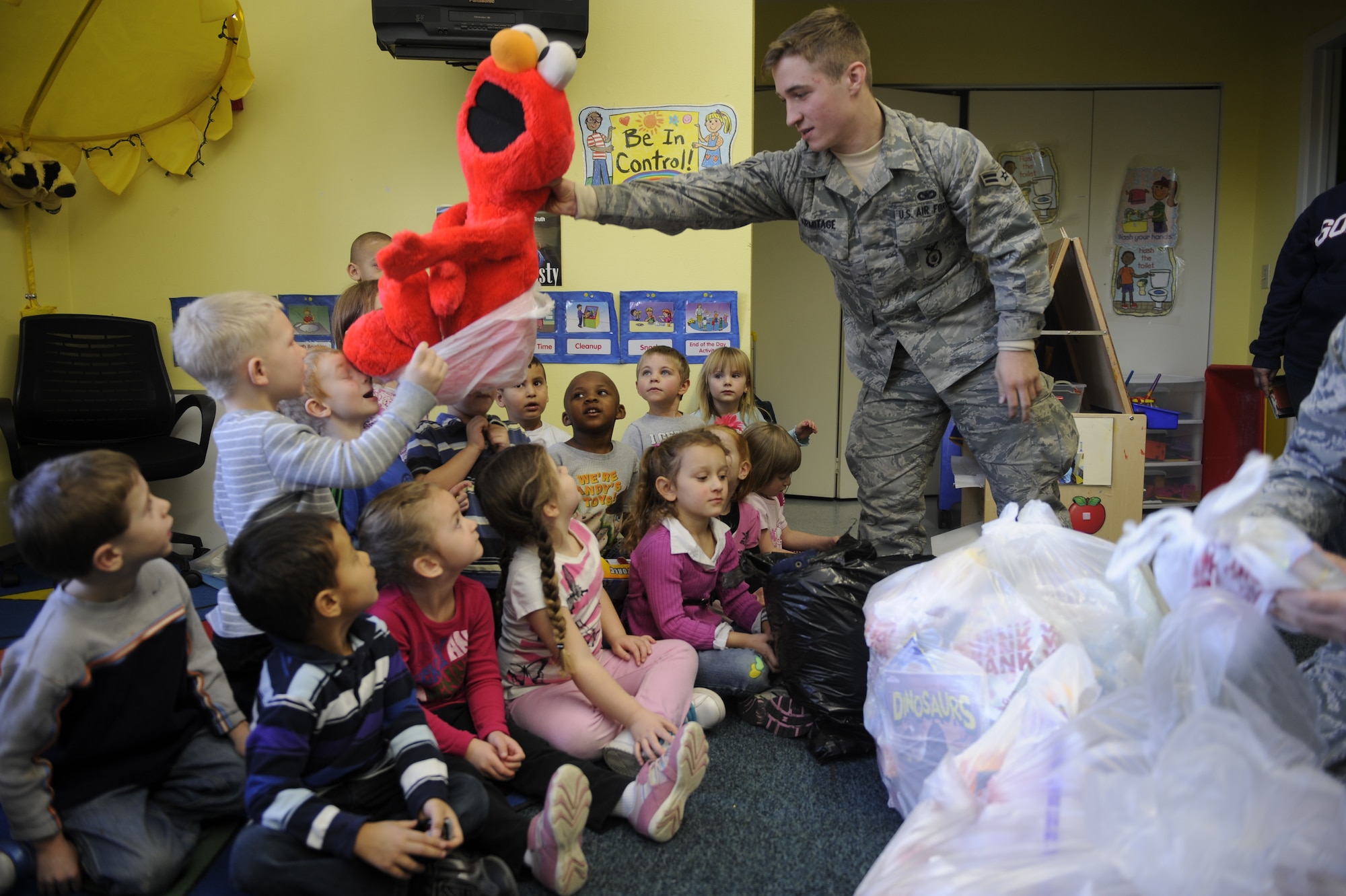 Airman 1st Class Christopher Armitage, 92nd Security Forces Squadron, hands out a stuffed Elmo, which he picked out personally to donate to children who attend Liberty Park Child Development Center’s Early Childhood Education and Assistance Program Dec. 12. (U.S. Air Force photo/Airman 1st Class Earlandez Young)