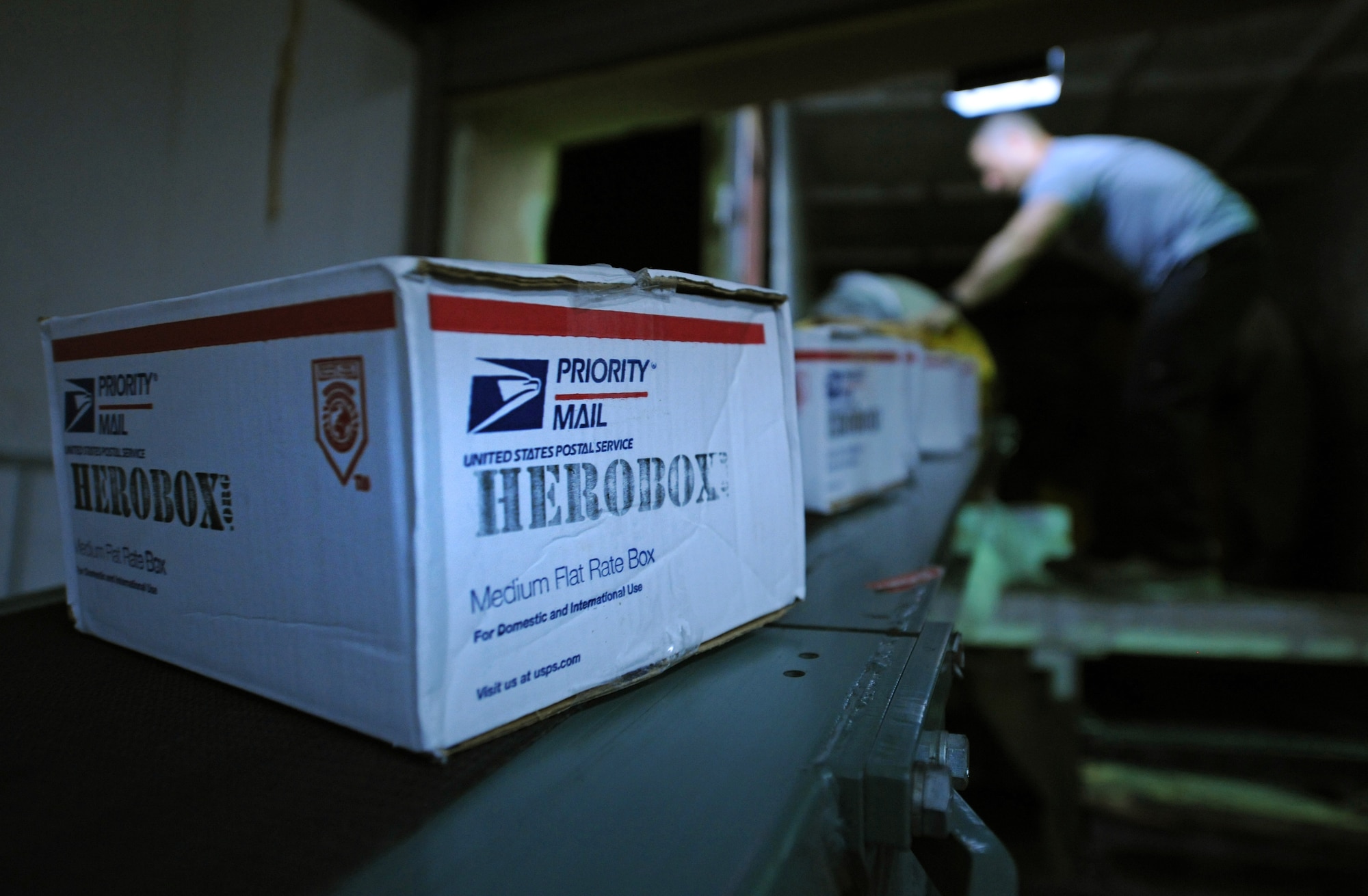 SOUTHWEST ASIA – Packages ride down a conveyor as Tech. Sgt. Ivan Abudo, 379th Expeditionary Communications Squadron Mail Control Activity chief and native of Dorado, Puerto Rico, unloads a truck here Dec. 21, 2011. Dec. 19-20 are typically the busiest processing days for mail centers across the United States, and the MCA here processed more mail in these two days than they do in an average work week. Abudo is deployed from Royal Air Force Menwith Hill, United Kingdom. (U.S. Air Force photo/Staff Sgt. Nathanael Callon)
