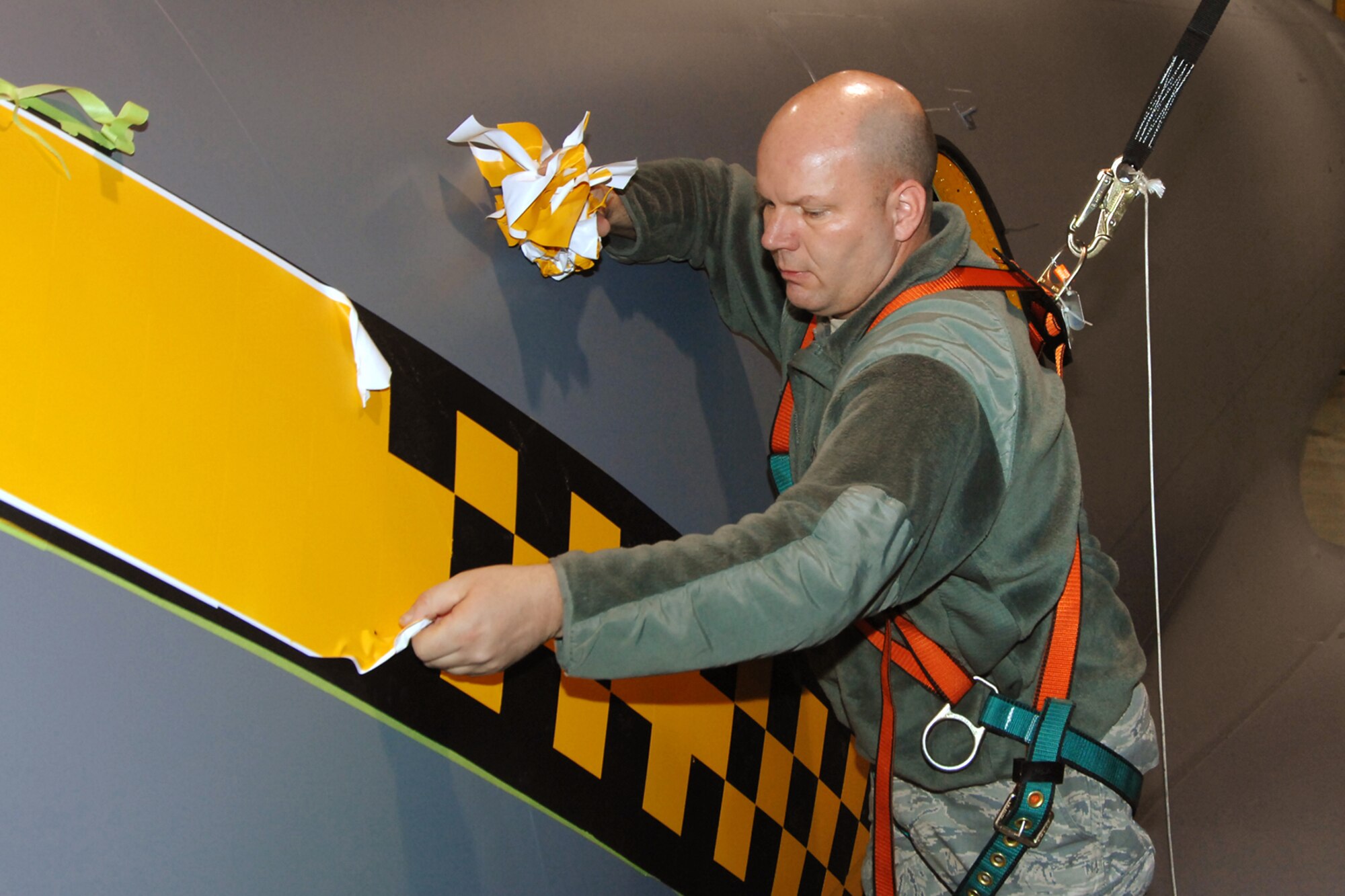 TSgt. Bart Davidson, 191st Maintenance Squadron, removes the masking tape from a checkerboard stripe newly-painted on a KC-135 Stratotanker at Selfridge Air National Guard Base, Mich., Dec. 15, 2011. The aircraft was painted with a checkerboard stripe and related detailing that honors both the heritage of the Michigan Air National Guard and the former Strategic Air Command, which once operated at Selfridge. (U.S. Air Force photo by SSgt. Rachel Barton)
