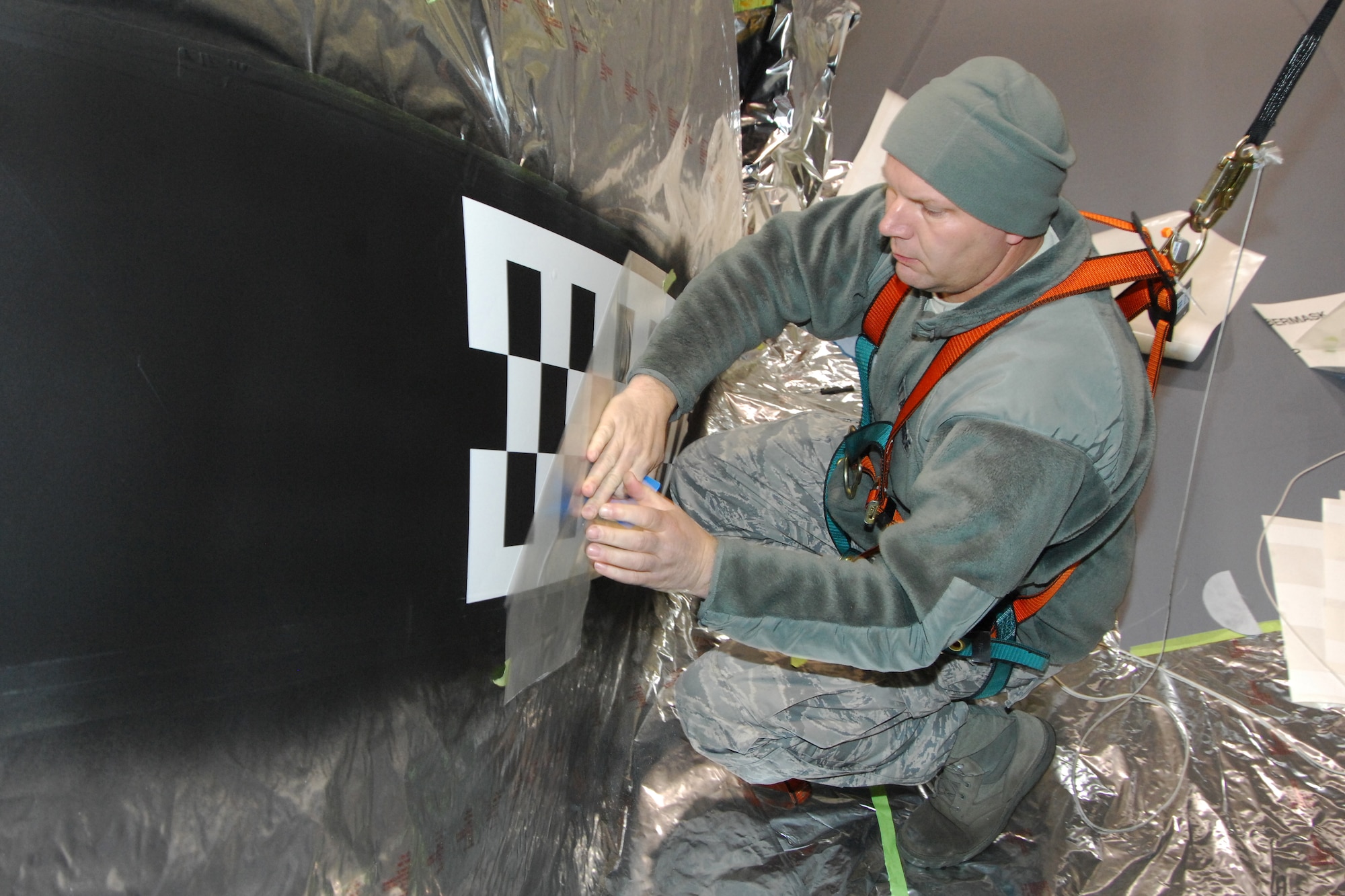TSgt. Bart Davidson, 191st Maintenance Squadron, applies a masking material during the painting process of applying a new paint scheme to a KC-135 Stratotanker at Selfridge Air National Guard Base, Mich., Dec. 13, 2011. The aircraft was painted with a checkerboard stripe that honors both the heritage of the Michigan Air National Guard and the former Strategic Air Command, which once operated at Selfridge. (U.S. Air Force photo by John S. Swanson)