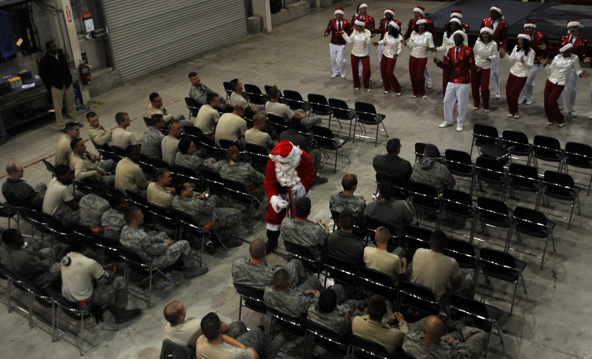 SOUTHWEST ASIA - Senior Airman "Kris Kringle" hands out presents to all the good Airmen while members of the Air Force entertainment group Tops in Blue  perform at their acoustic show at the aerospace ground equipment hangar Dec. 21, 2011. After their final performance of three shows here, Tops in Blue takes its show on the road to several other installations in Southwest Asia. During the year, Tops in Blue performs about 150 shows, with 25-30 of them at deployed locations. (U.S. Air Force photo/Staff Sgt. J.G. Buzanowski)