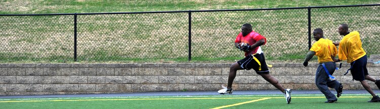 Christopher Brown, Marine Corps Institute Company offensive lineman and linebacker, catches a pass and outruns two defenders for a 50-yard gain during the second half of Marine Barracks Washington’s intramural flag-football championship here Dec. 21. After the 10-yard pass, Brown barreled down the sideline for an extra 40 yards and was downed at the opponent’s 9 yard line. Despite this touchdown drive late in the second half, Team MCI lost the game by eight points, 20-12. (Official Marine Corps Photo by Cpl. Austin Hazard/Released)::r::::n::