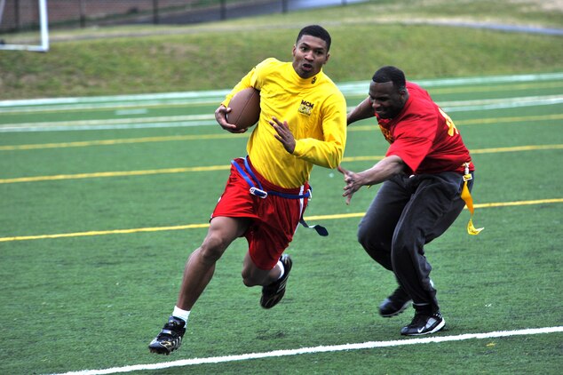 Brandon Mitchell, Headquarters & Service Company quarterback and cornerback, scrambles away from Christopher Adams, Marine Corps Institute Company linebacker, during the second half of Marine Barracks Washington’s intramural flag-football championship here Dec. 21. Mitchell surpassed 150 all-purpose yards in the game. His performance on offense and defense was a major factor in Team H&S’s 20-12 victory. (Official Marine Corps Photo by Cpl. Austin Hazard/Released)::r::::n::
