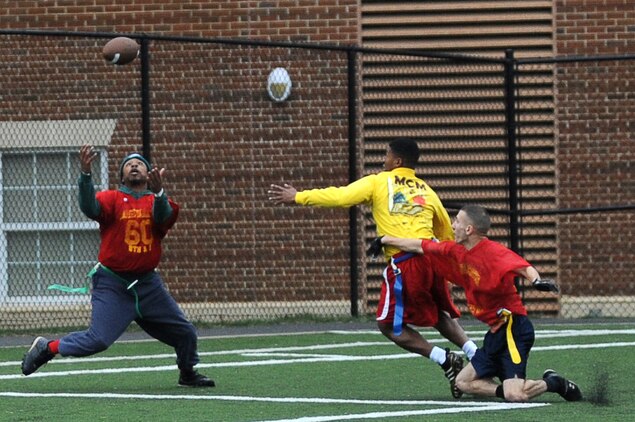 Sadiqq Abdullah, Marine Corps Company Institute Company wide receiver, catches a tipped pass for a touchdown from Alfredo Saenz, Team MCI quarterback, during the second half of Marine Barracks Washington’s intramural flag-football championship Dec. 21. Sadiqq caught the 50-yard bomb after Brandon Mitchell (yellow) unsuccessfully tried to intercept the pass in the end zone. Despite big plays and balanced drives, Team MCI lost the game 12-20. (Official Marine Corps Photo by Lance Cpl. Mondo Lescaud/Released)::r::::n::