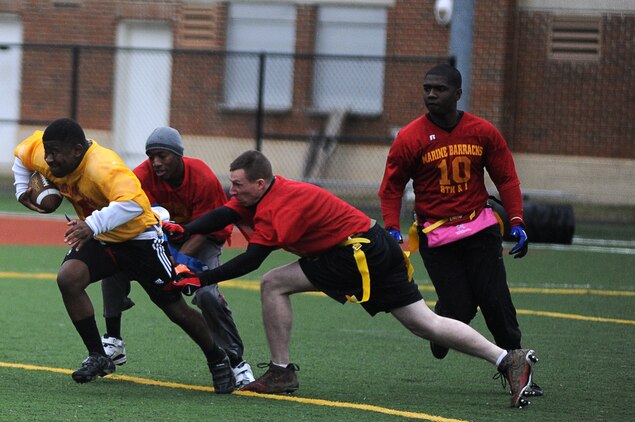 Wallace Logan, Headquarters & Service Company running back, steams through two defenders during the second half of Marine Barracks Washington’s intramural flag-football championship Dec. 21. Passionate players and smart play-calling enabled Team H&S’s 20-12 victory. (Official Marine Corps Photo by Lance Cpl. Mondo Lescaud/Released)::r::::n::