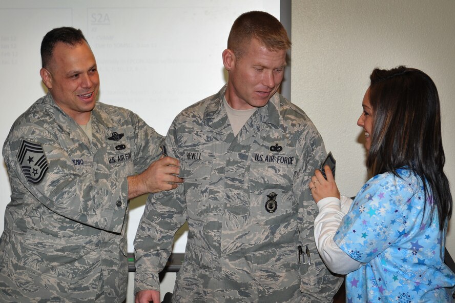 Tech. Sgt. Ernest Revell, 27th Special Operations Security Forces Squadron NCO in charge of operations staff support, has his rank tacked on by his wife Veronica and Chief Master Sgt. Matthew Caruso 27th Special Operations Wing command chief, at Cannon Air Force Base, N.M., Dec. 22, 2011. The new master sergeant earned his STEP promotion, or Stripes for Exceptional Performers, based on his potential to serve at a higher rank. (U.S. Air Force photo by Senior Airman Jette Carr)
