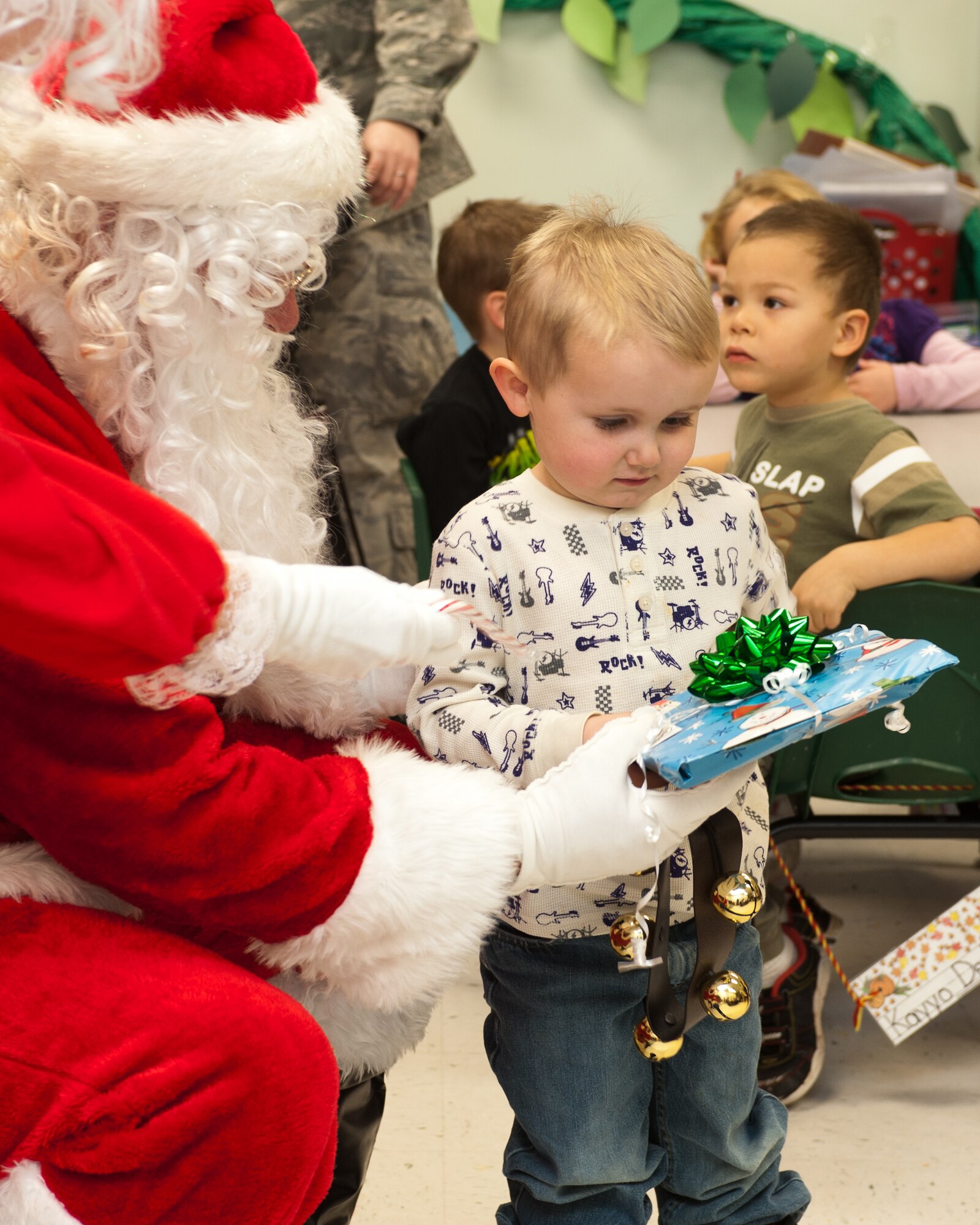 Santa Claus presents a gift to a child enrolled in the Youth & Family Services Child Care program in Rapid City, S.D., Dec. 15, 2011. More than 30 Ellsworth Air Force Base, S.D. Airmen volunteered to help Santa and Mrs. Claus hand out presents and candy canes to each child in the program. (U.S. Air Force photo by Airman Alystria Maurer/Released)