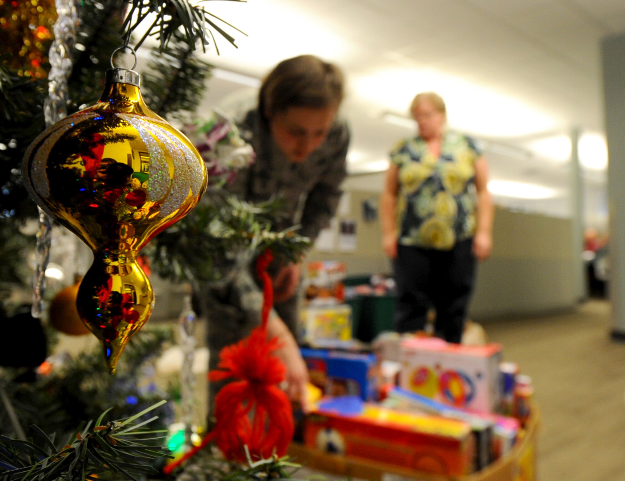 First Lt. Rebecca Gehrman, 28th Civil Engineer Squadron programs deputy flight chief, and Stacey Heverly, 28th CES office automation assistant, collect donated gifts from under the Gifts from the Heart tree on Ellsworth Air Force Base, S.D., Dec. 13, 2011. More than 150 people donated toys and gifts for underprivileged children in the local area. (U.S. Air Force photo by Airman 1st Class Zachary Hada/Released)