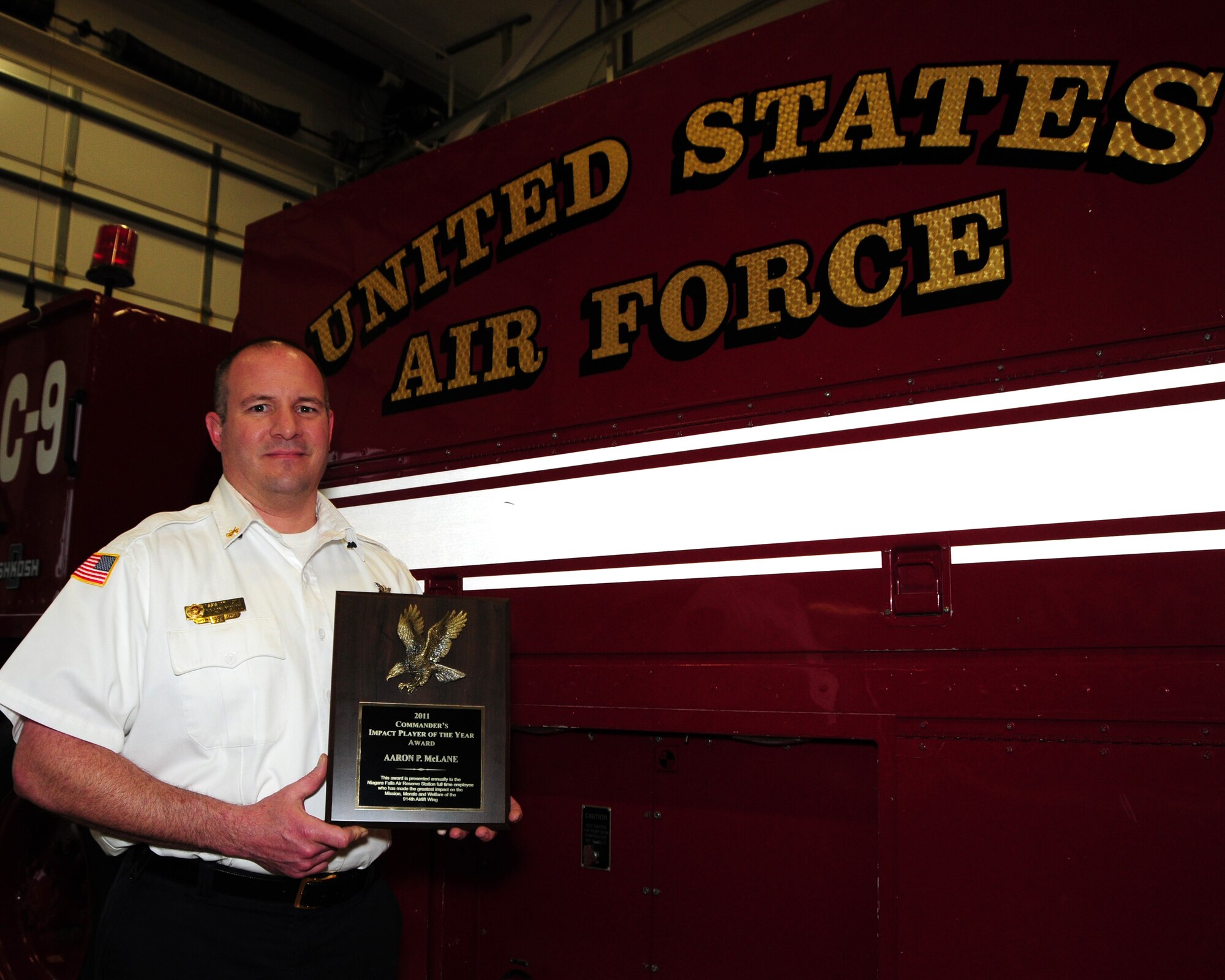 Assistant Fire Chief Aaron McLane, Niagara Falls Air Reserve Station Fire Department, displays the Impact Player of the Year Award he received on December 14, 2011. The award was presented to him by Col. Allan Swartzmiller, 914th Airlift Wing commander during a civilian commander's call to recognize Mr. McLane and others for their outstanding service and contributions to the wing. (U.S. Air Force photo by Peter Borys)