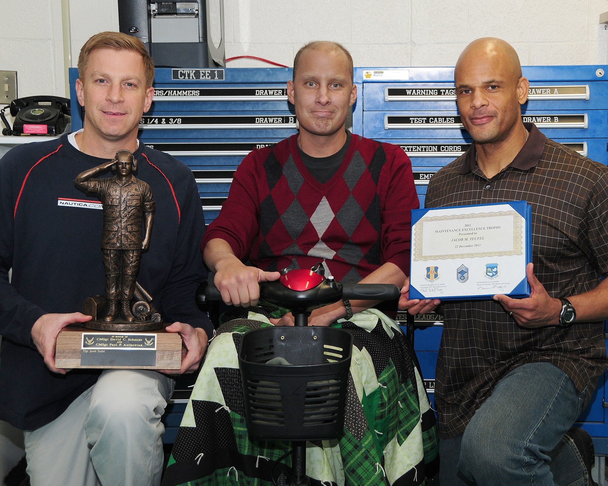 Lt. Col. Christopher Thurn, 107th Aircraft Maintenance Squadron commander (left) and Lt. Col. Kelvin McElroy, 914th Maintenance Group commander, (far right) pose with Tech. Sgt. Jacob Teufel, 914th Maintenance Squadron hydraulics technician with the 2011 Maintenance Excellence Trophy he received during an informal gathering at the Niagara Falls Air Reserve Station December 22. Teufel who is battling cancer is the first sole recipient to receive this joint 914 and 107 Airlift Wing award. (U.S. Air Force photo by Peter Borys)