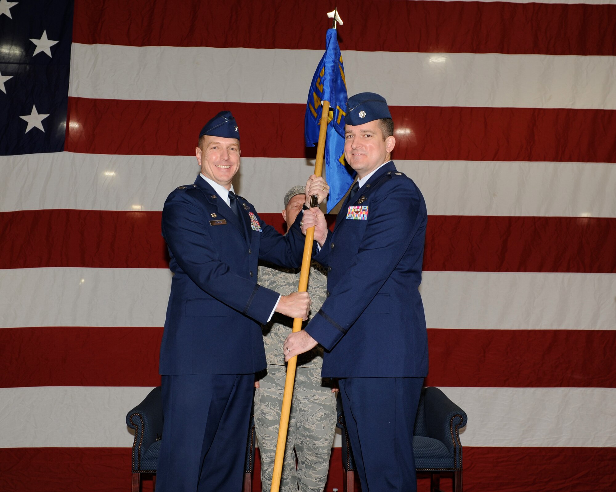 Col. Steve Stater, 14th Operations Group commander, passes the newly re-activated 14th Student Squadron guidon to its latest commander, Lt. Col. Jon Moore during the change of command ceremony in the BLAZE Hangar on Dec. 2. The 14th STURON first formed in 1946. (U.S. Air Force photo/Elizabeth Owens)