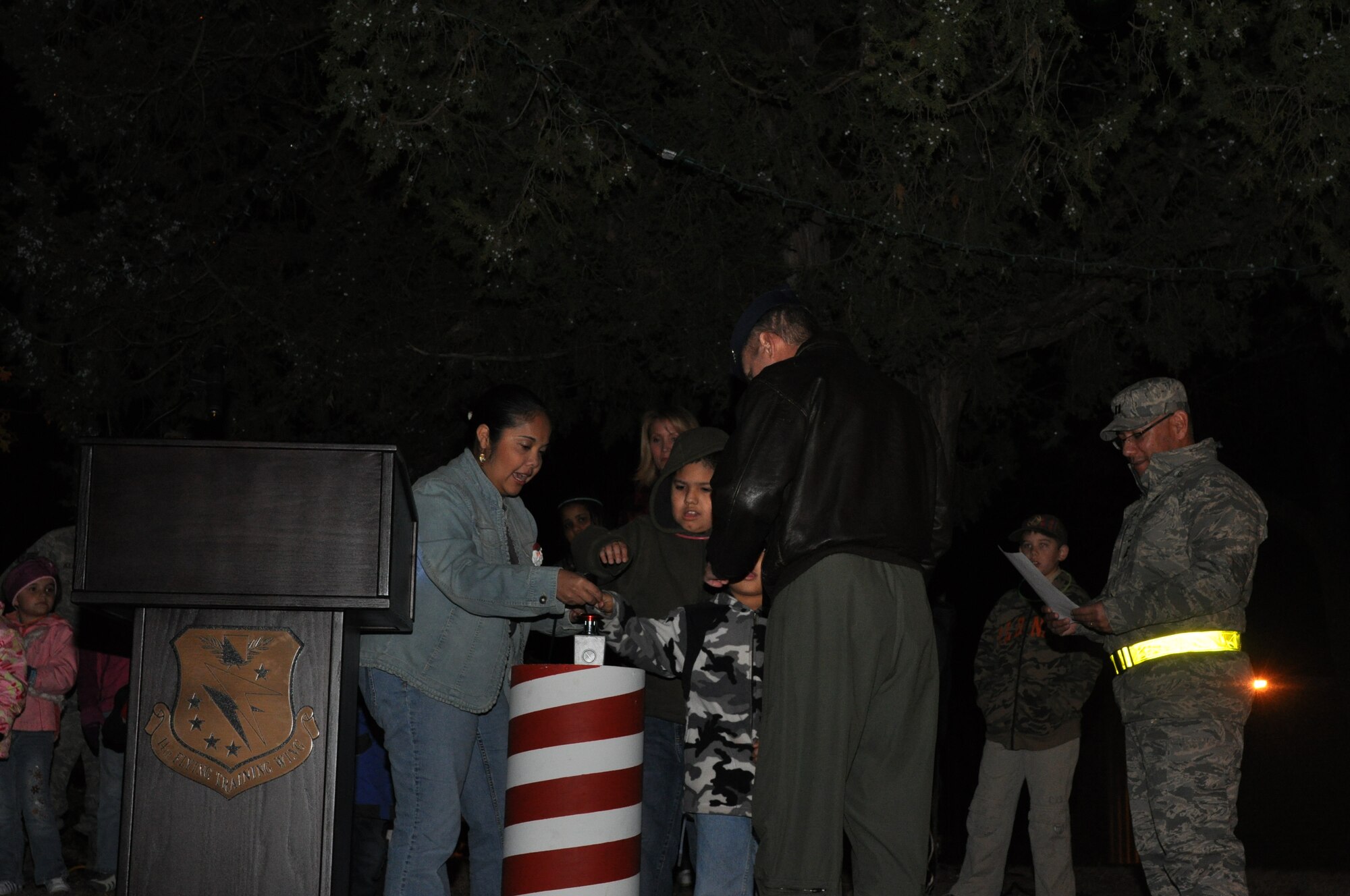 Veronica, Ramiro Jr. and Nick Castor, family members of currently deployed Staff Sgt. Ramiro Castro, turn on the Christmas tree lights during the 2011 Annual Team BLAZE Christmas Tree Lighting Ceremony held by the Base Chapel on Dec. 1. (U.S. Air Force photo/Airman 1st Class Charles Dickens)