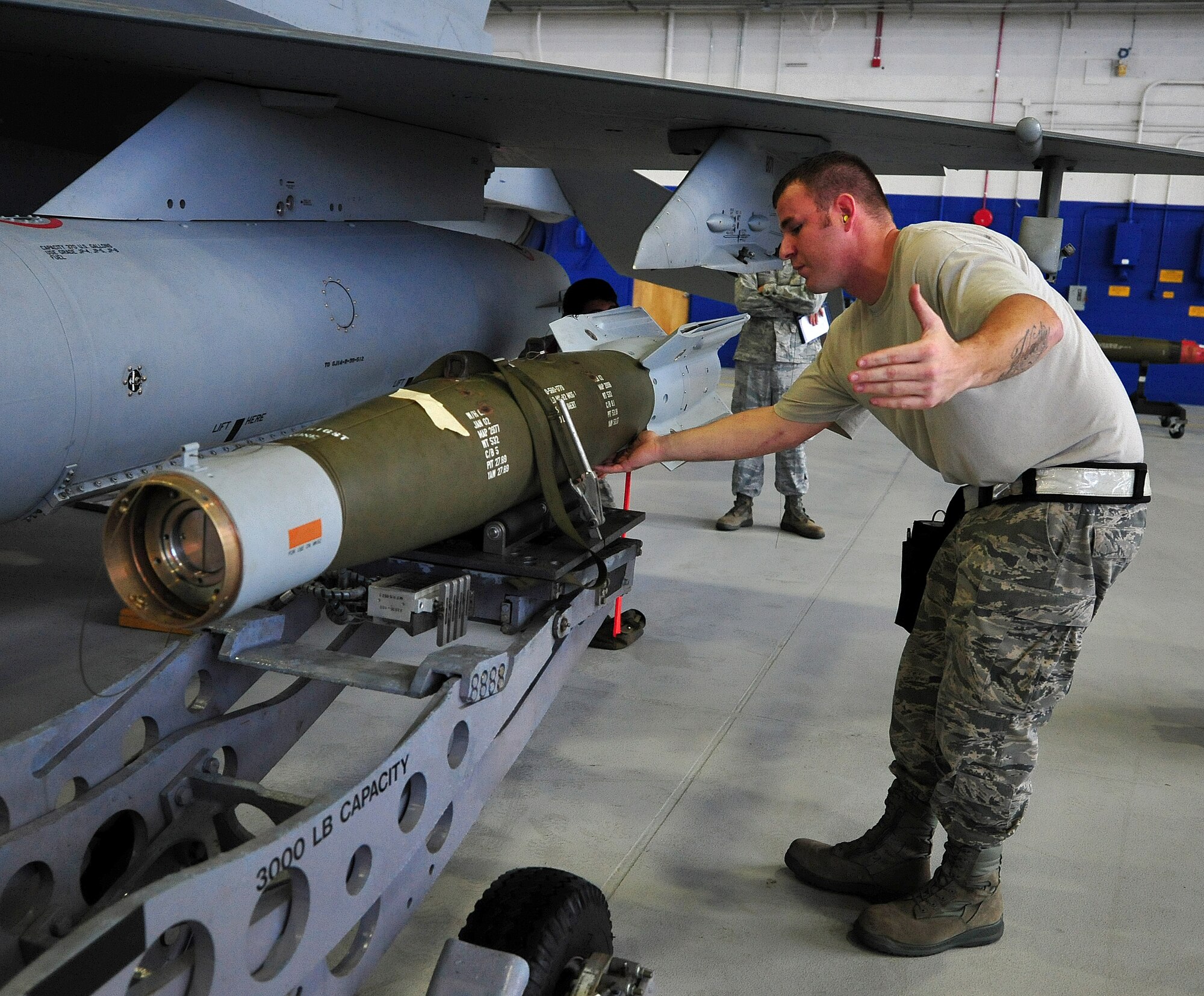 Staff Sgt. William Merritt, from the 46th Aircraft Maintenance Squadron, guides the GBU-12 onto the aircraft during the 46th Maintenance Group’s fourth quarter weapons load competition at Eglin Air Force Base, Fla., Dec. 21. The best of Blue AMU and Red AMU met to load an AIM-9 and GBU-12 onto an F-16 and F-15 respectively. AMU Red won the competition. (U.S. Air Force photo/Randy Gon) 