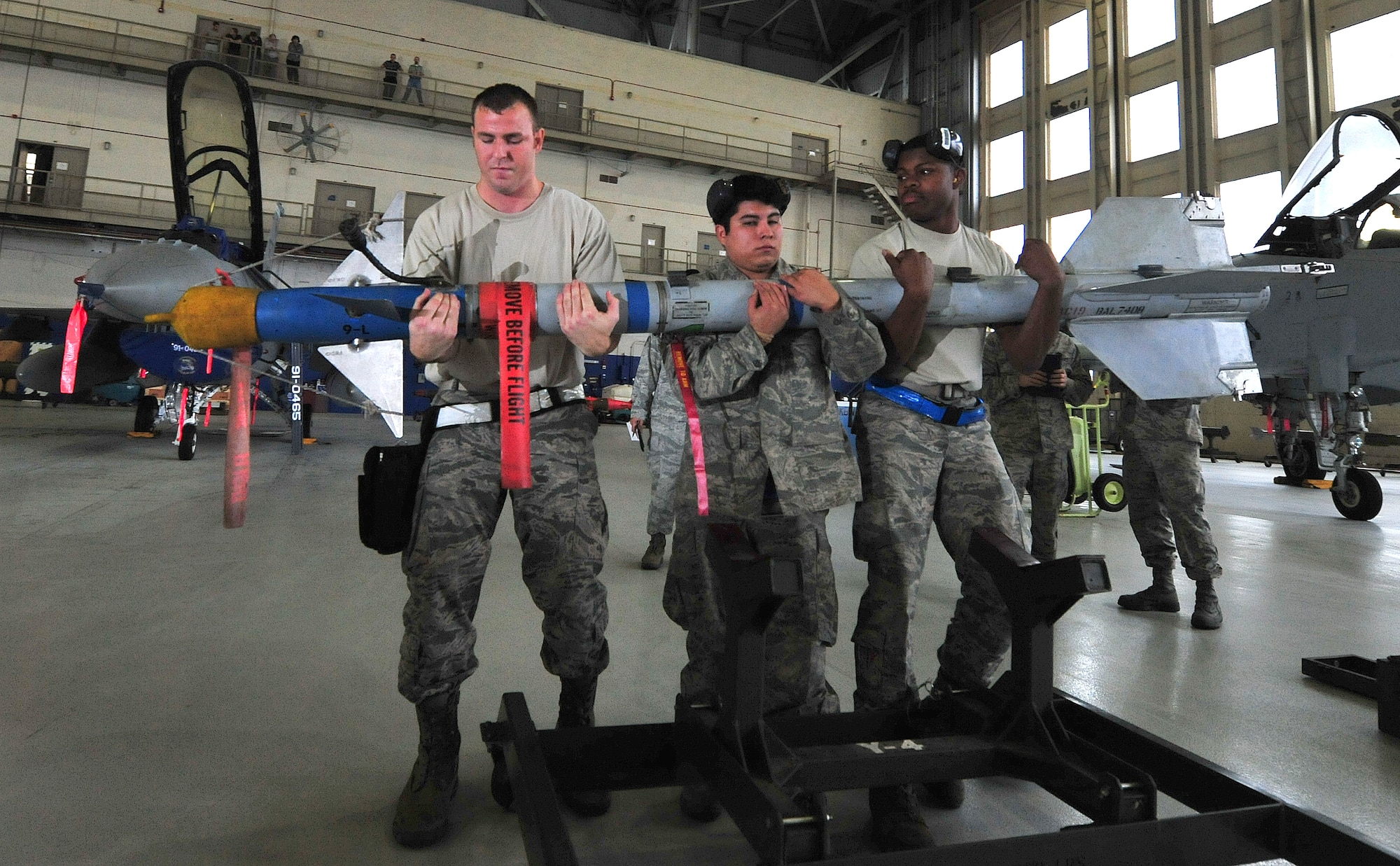 Staff Sgt. William Merritt, Senior Airman Victor Gonzalez and Airman 1st Class Adrian Justice, of the 46th Aircraft Maintenance Squadron, lift an AIM-9 during the 46th Maintenance Group’s fourth quarter weapons load competition at Eglin Air Force Base, Fla., Dec. 21. The best of Blue AMU and Red AMU met to load an AIM-9 and GBU-12 onto an F-16 and F-15 respectively. AMU Red won the competition. (U.S. Air Force photo/Randy Gon) 