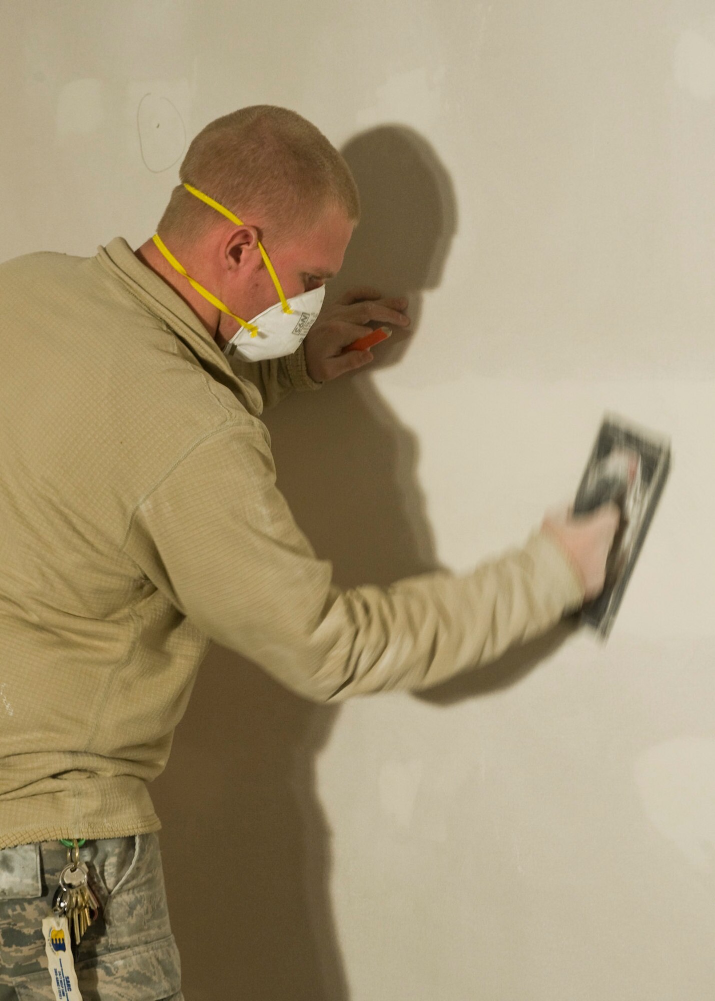 Airman 1st Class Michael Corman, 28th Civil Engineer Squadron structural journeyman, sands down uneven surfaces on the walls of the restroom currently under construction at the Pride Hangar on Ellsworth Air Force Base, S.D., Dec. 13, 2011. The project scheduled to be finished by Jan. 30, 2011, will provide Airmen who use the Pride Hangar completely renovated restroom facilities. (U.S. Air Force photo by Airman Alystria Maurer/Released)