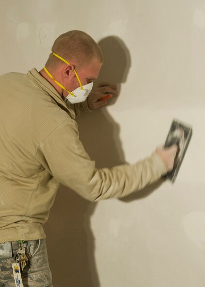 Airman 1st Class Michael Corman, 28th Civil Engineer Squadron structural journeyman, sands down uneven surfaces on the walls of the restroom currently under construction at the Pride Hangar on Ellsworth Air Force Base, S.D., Dec. 13, 2011. The project scheduled to be finished by Jan. 30, 2011, will provide Airmen who use the Pride Hangar completely renovated restroom facilities. (U.S. Air Force photo by Airman Alystria Maurer/Released)