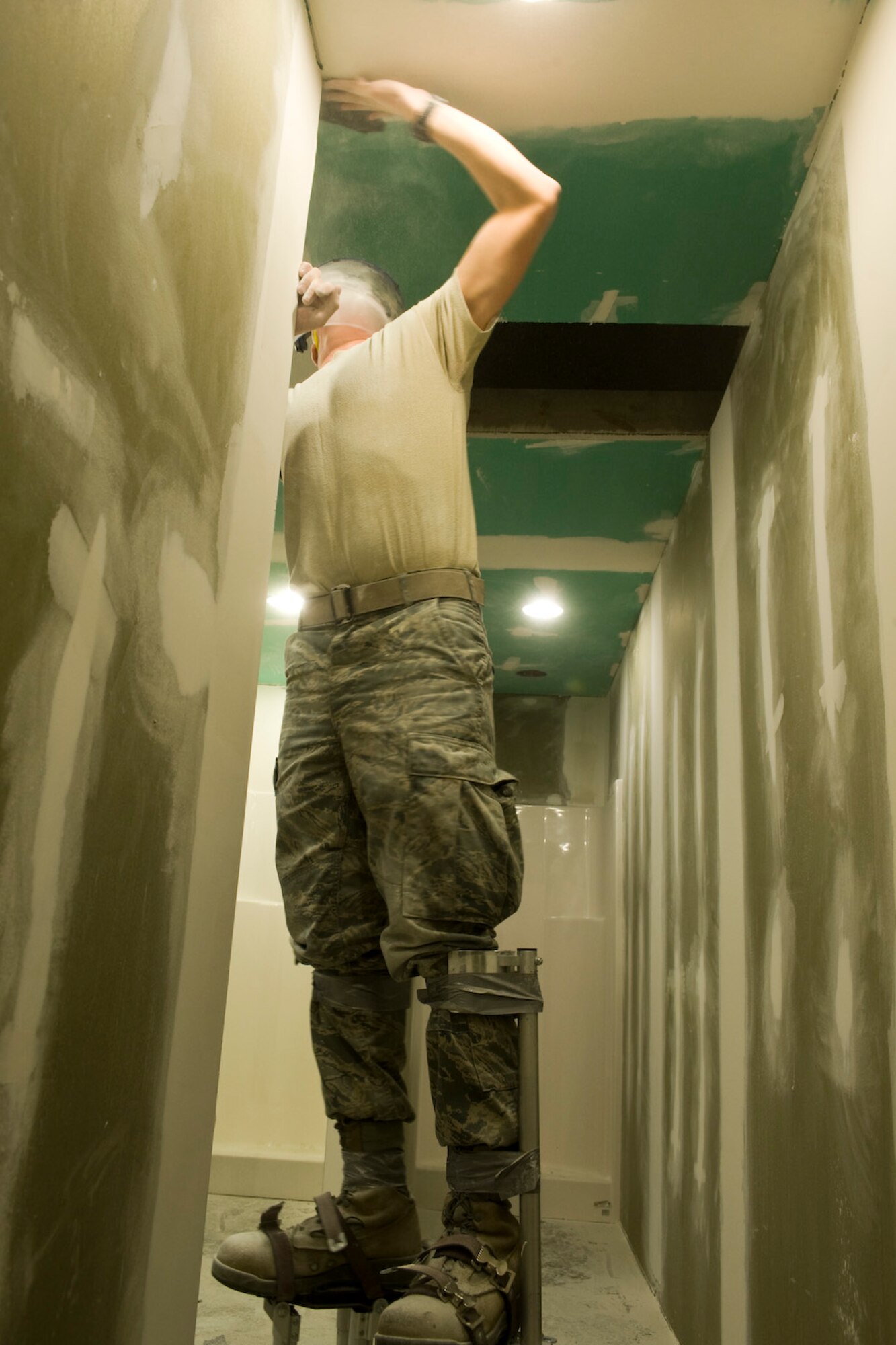 Airman 1st Class Benjamin Parker, 28th Civil Engineer Squadron structural journeyman, uses sandpaper to smooth the ceiling surface before applying a coat of paint in a restroom under construction at the Pride Hangar on Ellsworth Air Force Base, S.D., Dec. 13, 2011. Airmen from the 28th CES are adding showers and locker rooms to the restrooms, as a way of improving the quality of life for Airmen who use the Pride Hangar. (U.S. Air Force photo by Airman Alystria Maurer/Released)