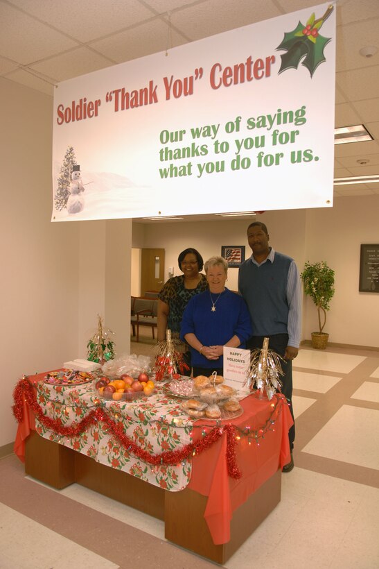 Lani Gates, Gayle West and Geoff Tyrone of the 733rd Mission Support  Group Soldier Support Center show off their “Soldier ‘Thank You’ Center” table Dec. 15 at the Fort Eustis 733rd Mission Support  Group Soldier Support Center. The entire SSC donated items such as fruits, donuts, cookies and apple cider to give to servicemembers during the holiday season as a way of thanking them for all they do for their country. (U.S. Air Force photo by Staff Sgt. Jeff Nevison/Released)