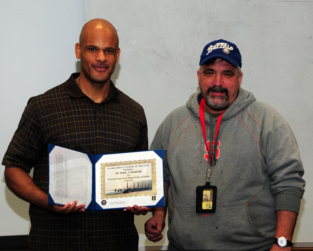 Lt. Col. Kelvin McElroy, 914th Maintenance Group commander, (left) presents the 914th Maintenance Group Impact Player of the Year Award to Mr. Dennis Paradowski, 914th Maintenance Squadron propulsion technician, during an informal gathering at the Niagara Falls Air Reserve Station on December 22, 2011. Mr. Paradowski, retired in 1996 after serving 20 years as an Air Force Reservist, but continues to serve his country as a civilian. (U.S. Air Force photo by Peter Borys)