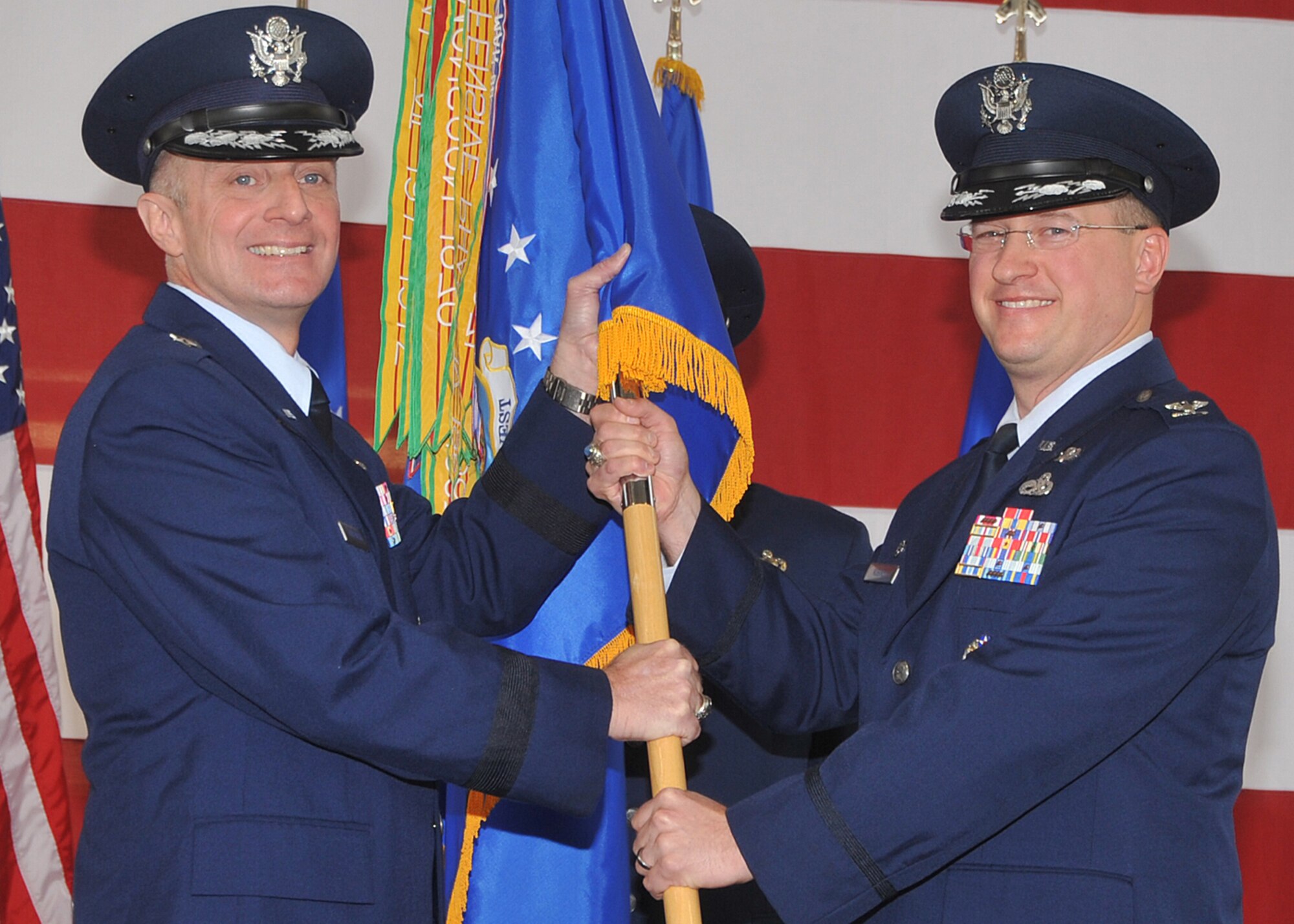 During an assumption of command ceremony Dec. 19, Brig. Gen. Garrett Harencak, Air Force Nuclear Weapons Center commander, left, passes the guidon to Col. John C. Kubinec, the new 377th Air Base Wing commander. U.S. Air Force Photo by Todd Berenger