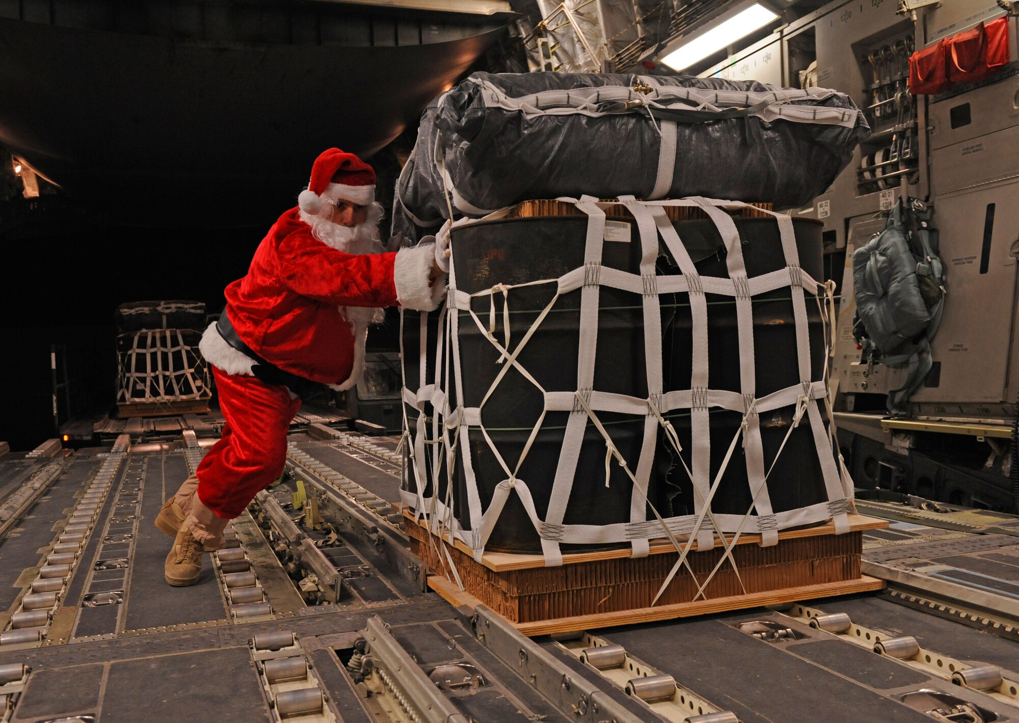 SOUTHWEST ASIA – Santa Claus, portrayed by Tech. Sgt. Mike Morris, 816th Expeditionary Airlift Squadron Loadmaster Flight NCO in charge and native of Charleston, S.C., pushes a pallet of fuel onto a C-17 Globemaster III prior to a mission here Dec. 23, 2011. The 816th EAS airdropped 40 pallets of fuel to remote forward operating bases in Afghanistan. The fuel will be used for generators, heaters and vehicles. Morris is deployed from Charleston Air Force Base, S.C. (U.S. Air Force photo/Staff Sgt. Nathanael Callon)