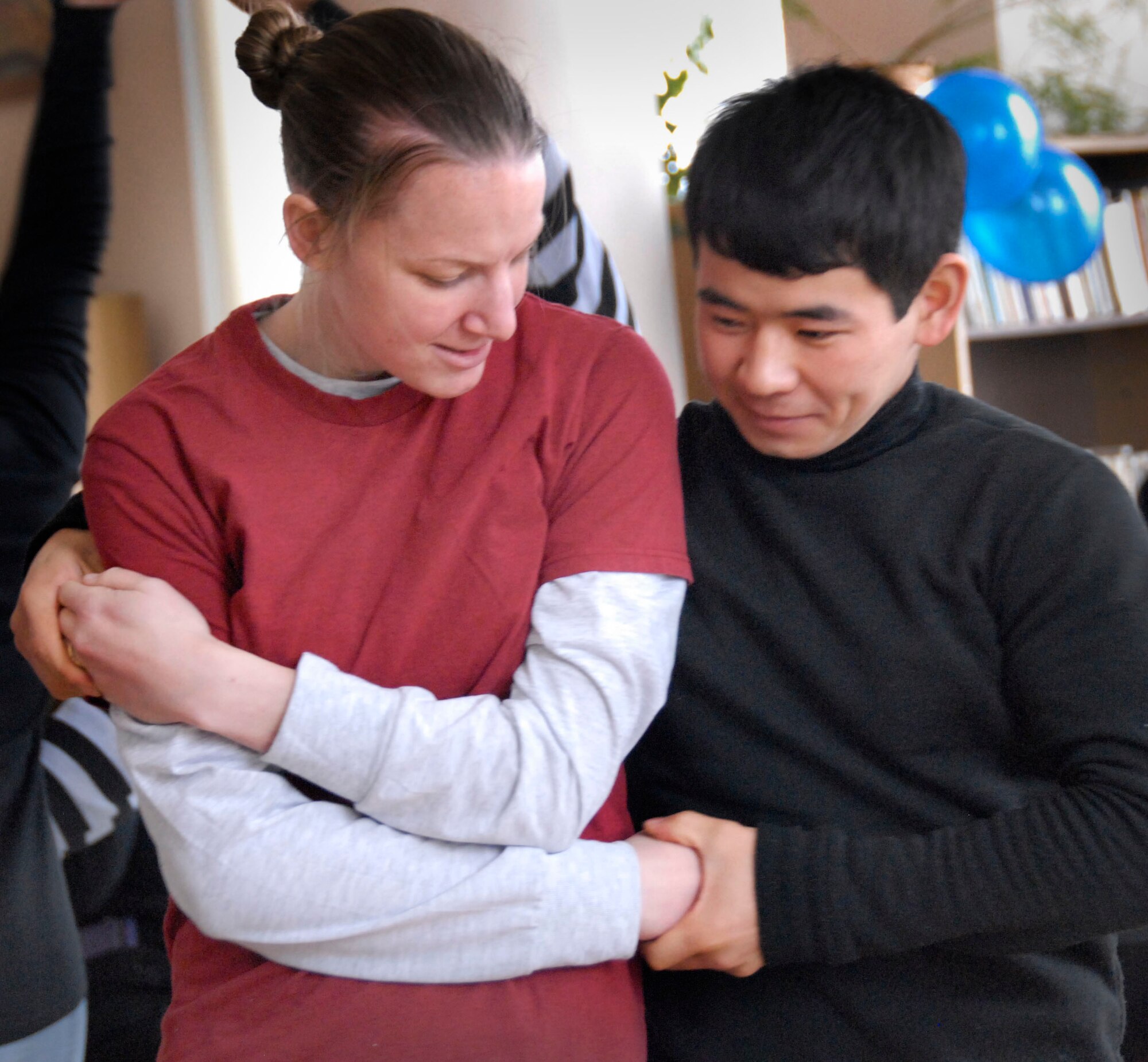 TRANSIT CENTER AT MANAS, Kyrgyzstan -- Staff Sgt. Kristin Parsons, 376th Expeditionary Medical Group NCO in charge of laboratory services, demonstrates a dance move to a Kyrgyz student Dec. 20, 2011 during a visit to Bayalinov Library. Parsons and other Transit Center Airmen are part of a cultural exchange project called "American Corner." The group travels to local areas to teach the population about the American culture and to learn about Kyrgyz culture as well. Parsons is deployed from Lackland Air Force Base, Texas. (U.S. Air Force photo/ Senior Airman Lynsie Nichols)