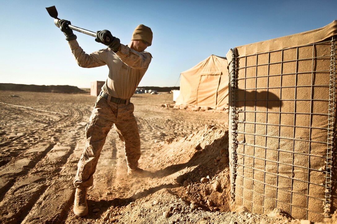 U.S. Marine Corps Lance Cpl. Paul Flores uses a pick axe to clear away dirt from a HESCO barrier so it can be dismantled on Firebase Saenz in Afghanistan's Helmand province, Dec. 14, 2011. Flores is a combat engineer assigned to Alpha Company, 9th Engineer Support Battalion.