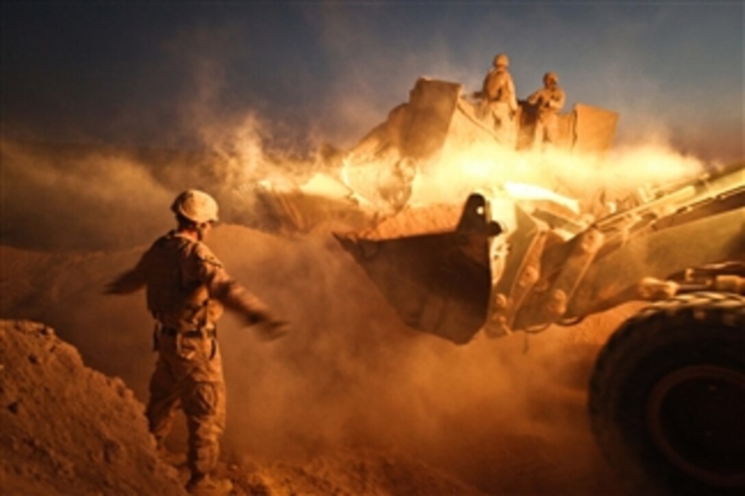 Sgt. Cody Palfreyman, a combat engineer with Alpha Company, 9th Engineer Support Battalion, guides a bulldozer as it moves the berm surrounding a guard post at Firebase Saenz, Helmand province, on Dec. 14, 2011.  Firebase Saenz is the first of several patrol bases being demilitarized by the Marines of 9th Engineer Support Battalion throughout the month of December.  