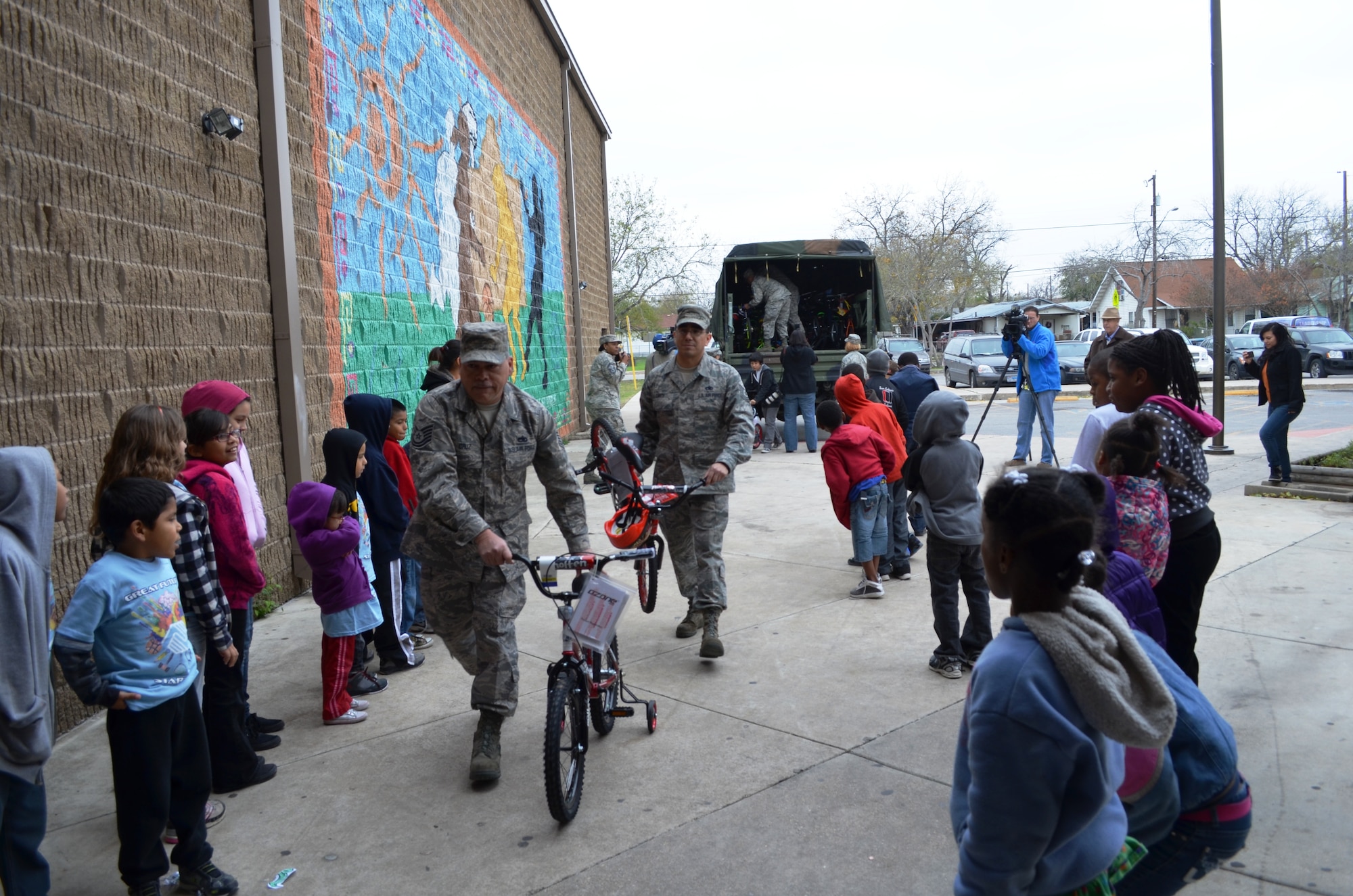 Excited Boys & Girls Club members greet Tech Sgts. James Cruz and Jesse Cantu as they deliver  two of the 63 bikes donated by the 433rd Airlift Wing. For the third consecutive year, the Alamo Wing Top Three gathered bikes and safety equipment to donate to children in need. Youth were selected on the basis of participation, behavior, and grades by Boys & Girls Club staff members from branches throughtout San Antonio, Texas. (U.S. Air Force photo/ Tech Sgt. Carlos J. Trevino)  