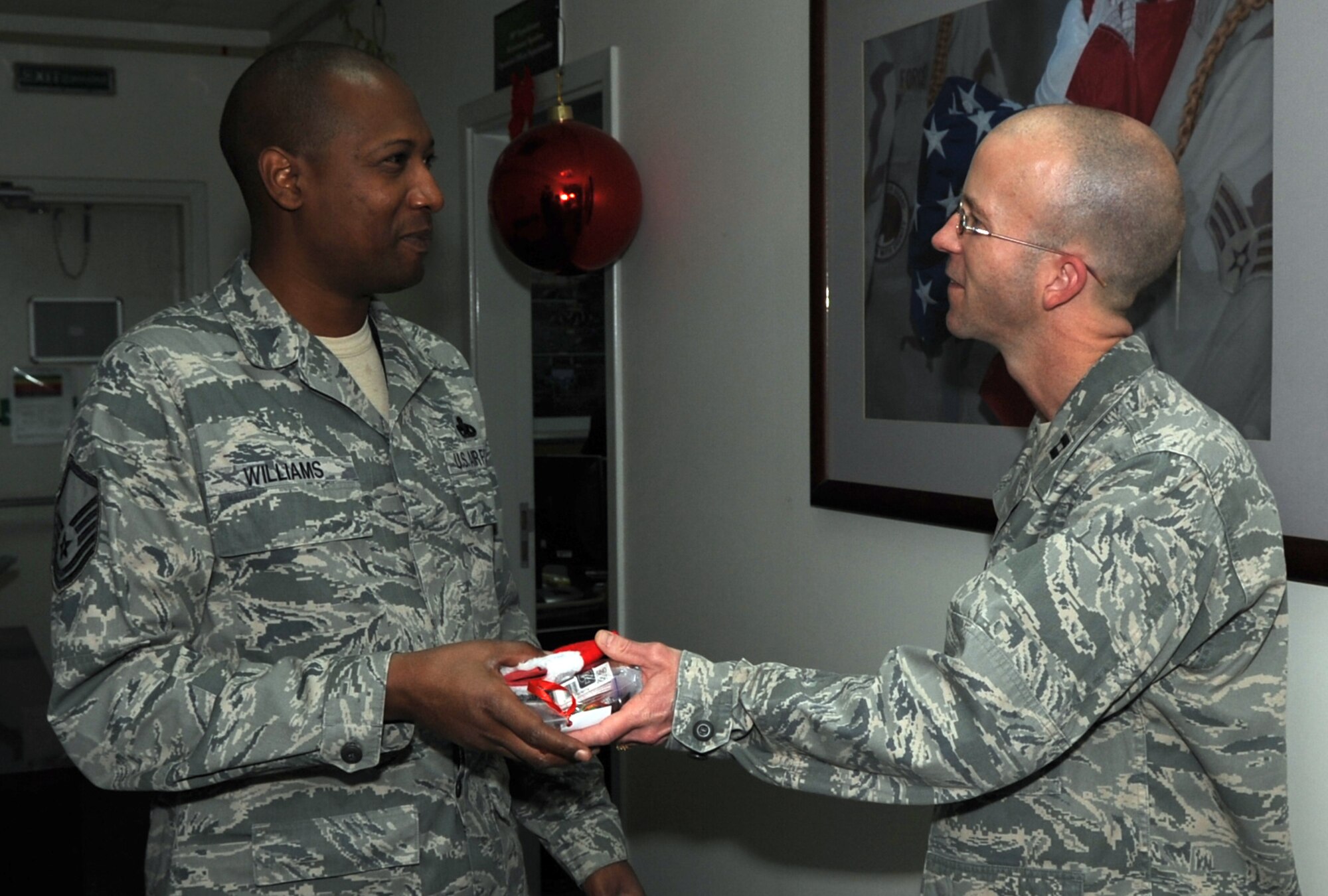 SOUTHWEST ASIA - Chaplain (Capt.) Rolf Holmquist offers a stocking to Master Sgt. Phillip Williams Dec. 22, 2011. Over the past several weeks, the chapel staff collected thousands of items for their Operation: Holiday Blitz. Roughly 40 volunteers helped them put together stockings for everyone deployed here. (U.S. Air Force photo/Staff Sgt. J.G. Buzanowski)