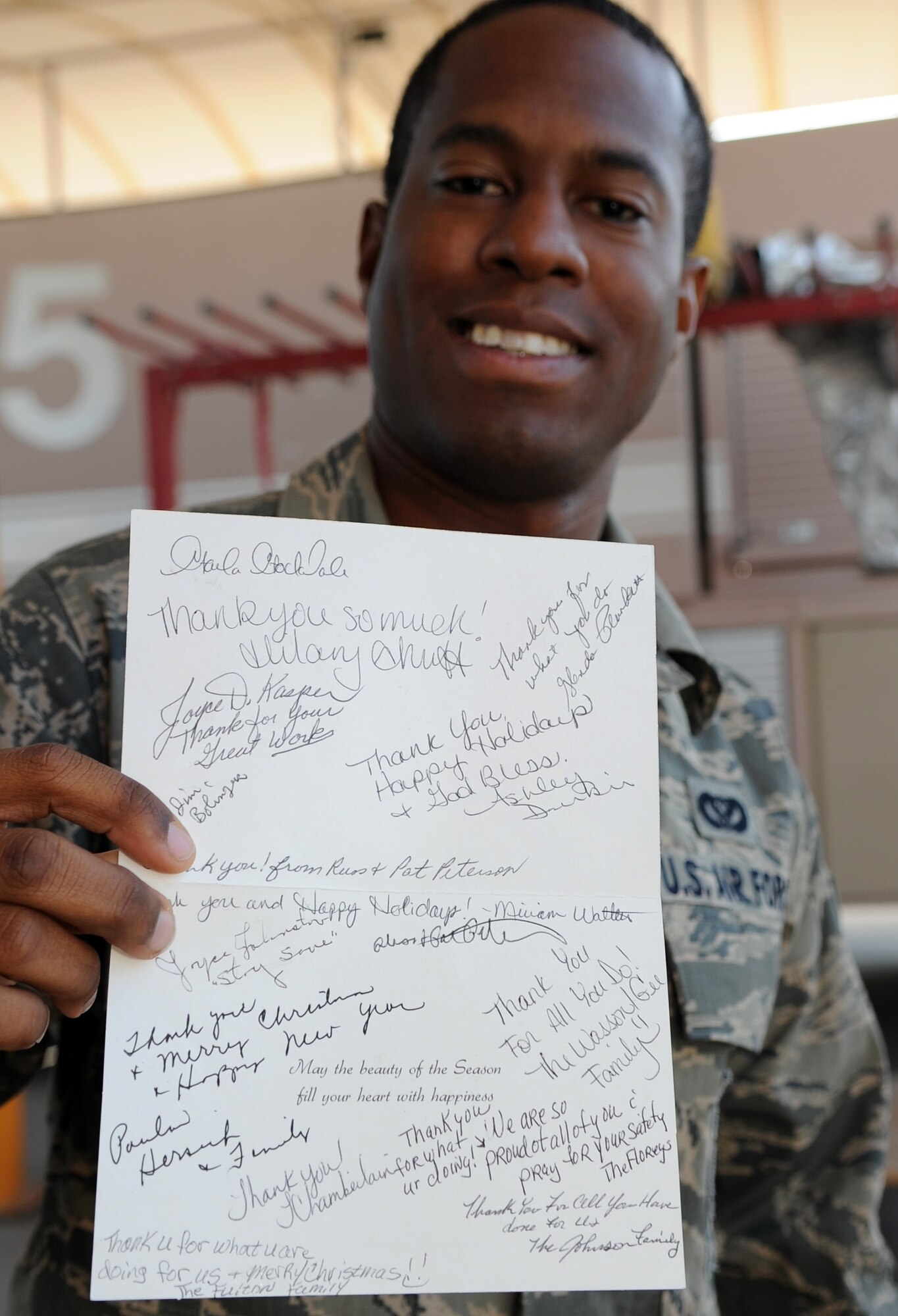 SOUTHWEST ASIA - Airman 1st Class Brian Lovelady holds up a card Dec. 22, 2011 showing words of support from residents of Neoga, Ill. Members of the 380th Air Expeditionary Wing chapel staff handed out cards and stockings to everyone deployed here as part of their Operation: Holiday Blitz. Roughly 40 volunteers helped the staff put together stockings with candy and other items for everyone deployed here. Lovedlady is a firefighter deployed from Andersen Air Force Base, Guam. (U.S. Air Force photo/Staff Sgt. J.G. Buzanowski)