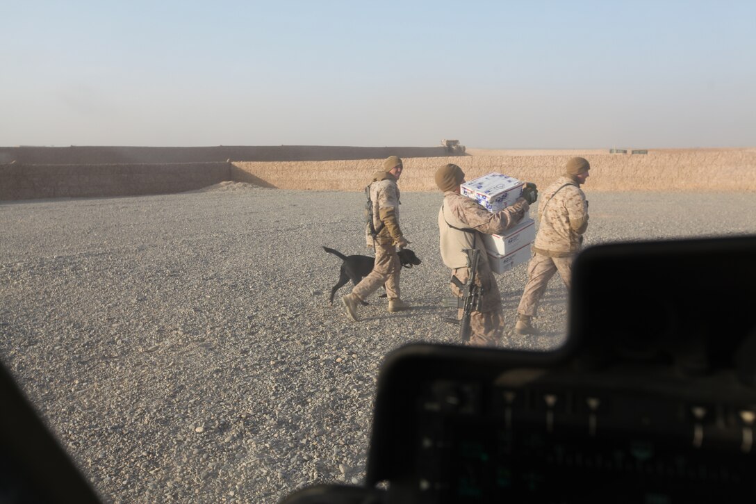 Marines at a forward operating base in Helmand province, Afghanistan, carry care packages delivered by Marine Light Attack Helicopter Squadron 369, Dec. 25. The Marine Corps helicopter squadron flew thousands of pounds of care packages to infantry Marines at austere combat outposts in Afghanistan on Christmas Day.::r::::n::::r::::n::::r::::n::