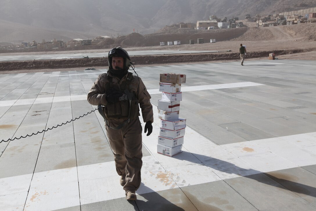 Marines at a forward operating base in Helmand province, Afghanistan, carry care packages delivered by Marine Light Attack Helicopter Squadron 369, Dec. 25. The Marine Corps helicopter squadron flew thousands of pounds of care packages to infantry Marines at austere combat outposts in Afghanistan on Christmas Day.::r::::n::::r::::n::::r::::n::