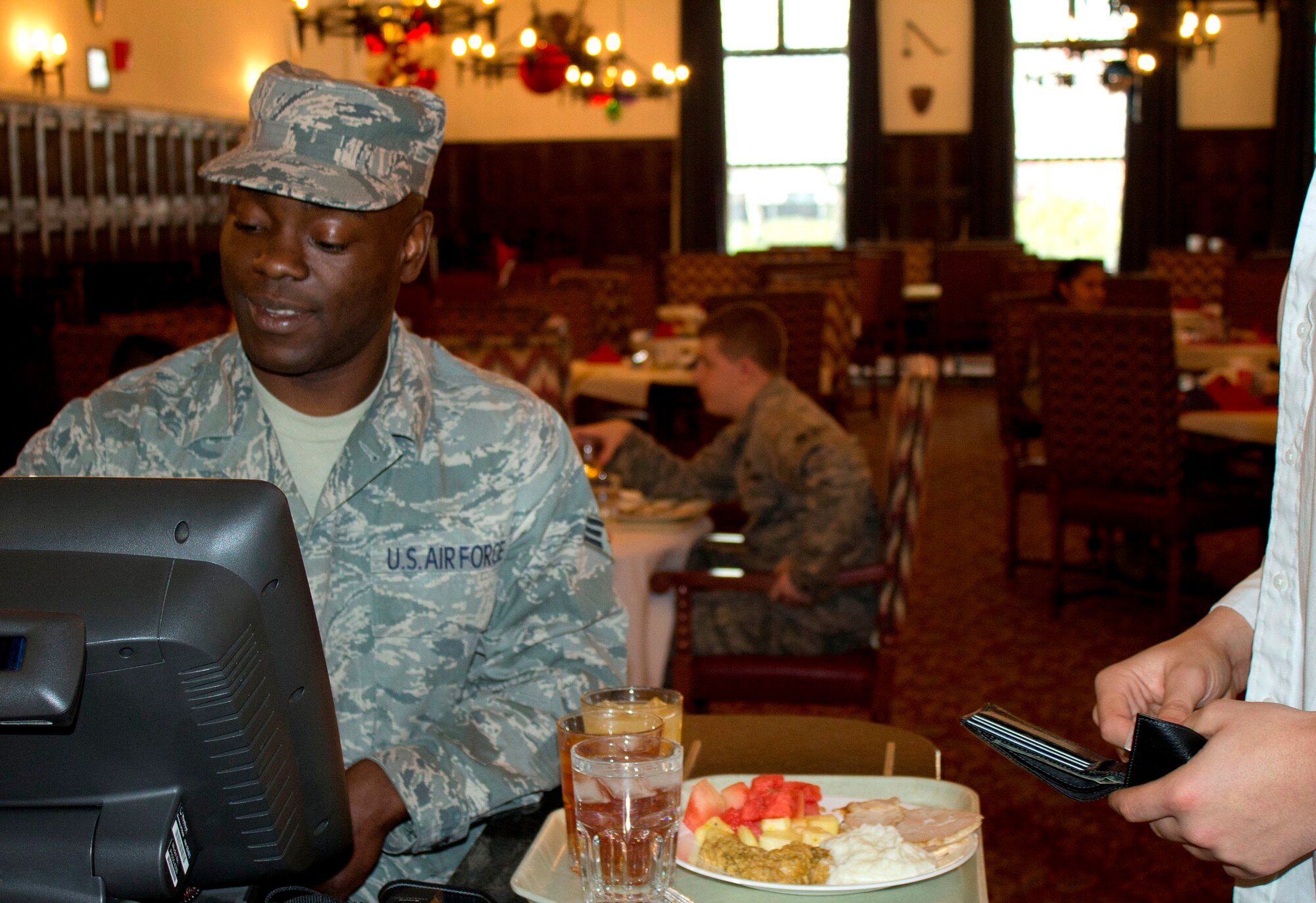 RAF MILDENHALL, England – Senior Airman Ebot Leonel, 100th Force Support Squadron, rings up a customer at the RAF Mildenhall Dining Facility here on Christmas Day. Leonel is from Cameroon, Africa, and said he would celebrate Christmas at home in the same fashion as is common in the United States. Although he misses his family, Leonel is hopeful they will get to visit him here soon. (U.S. Air Force photo/1st Lt. Jason Smith)