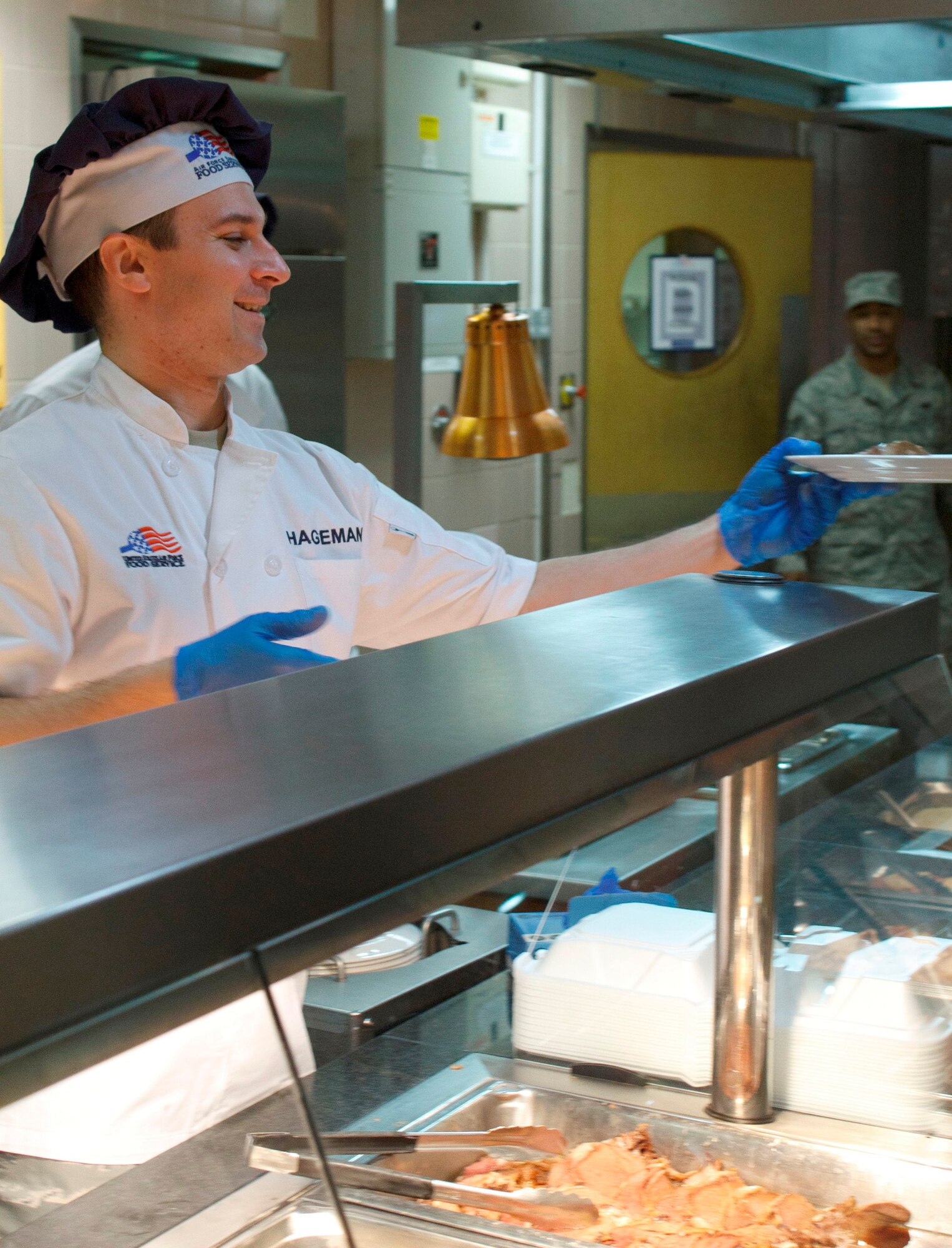 RAF MILDENHALL, England –Lt. Col. Chris Hageman, 100th Force Support Squadron commander, serves a Christmas meal to an Airman at the RAF Mildenhall Dining Facility here on Christmas Day. The meal included prime rib, turkey, ham, shrimp cocktail and “all of the fixins,’”said Hagemen. Hageman said Master Sgt. Michael Francis, the dining facility manager, and the entire staff worked hard to put the meal together. (U.S. Air Force photo/1st Lt. Jason Smith)