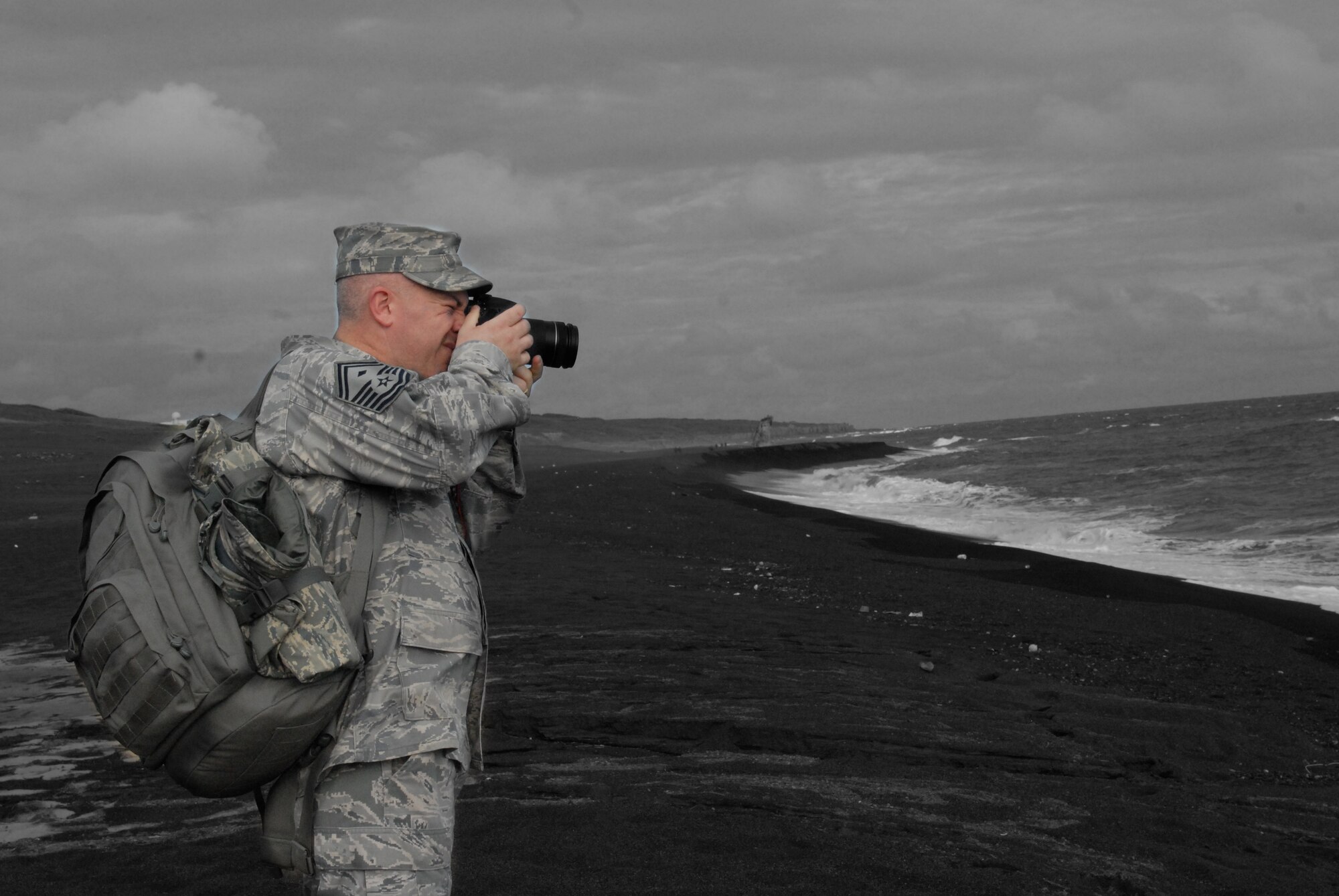 U.S. Air Force Senior Master Sgt. Christopher Moore, 18 Equipment Maintenance Squadron first sergeant, stops to take a photo on the beach of Iwo Jima, during a trip to Mount Suribachi, Iwo Jima, Japan, Dec. 22, 2011. This trip afforded an opportunity for the 18th Wing to share this experience with their Marine Corps brethren. (U.S. Air Force photo illustration by Tech Sgt. Lakisha A. Croley/released)