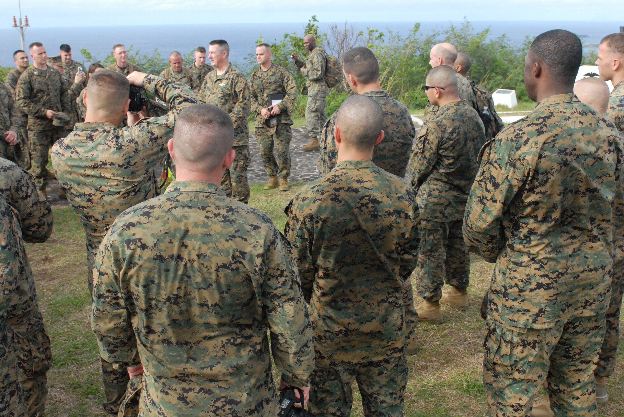 U.S. Marine Corpsmen from the 1st Marine Aircraft Wing gather together on top of Mount Suribachi to pay homage to a fallen Marine whose ashes were scattered over the edge of the summit during a trip to Iwo Jima, Dec. 22, 2011. This was hopefully the first of many occasions to come when members of the 18th Wing will be able to accompany the men and women of the 1st Marine Aircraft Wing, Futenma Air Station on this trip. (U.S. Air Force photo by Tech Sgt. Lakisha A. Croley/released)