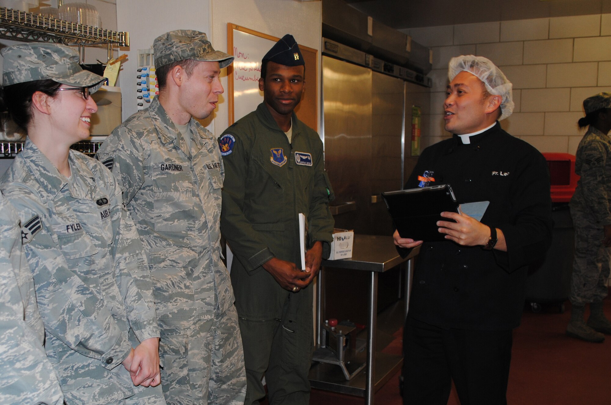 From left, Senior Airman Eleanor Fyler, missile chef with the 10th Missile Squadron; Staff Sgt. Eldoris Gardner, missile chef with the 12th Missile Squadron; and Capt. Jonathan Brydie, missile combat crew commander with the 10th MS, talk about cooking and wait to have a book autographed by Father Leo Patalinghug, host of the television show, "Grace Before Meals," and author of "Grace Before Meals; Recipes for family life."