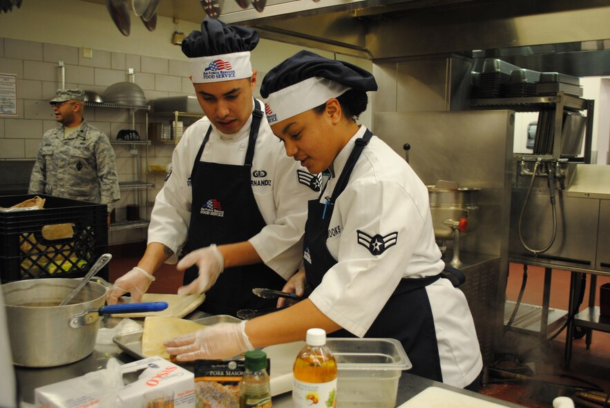 Senior Airman Frank Hernandez and Senior Airman Estrella Zapata-Brooks, both missile chefs with the 12th Missile Squadron, prepare apple egg rolls for their winning dish during the 4th quarter Warrior Chef Competition Dec. 16. The secret ingredient for the competition was apples. (U.S. Air Force photo/Airman 1st Class Katrina Heikkinen)

