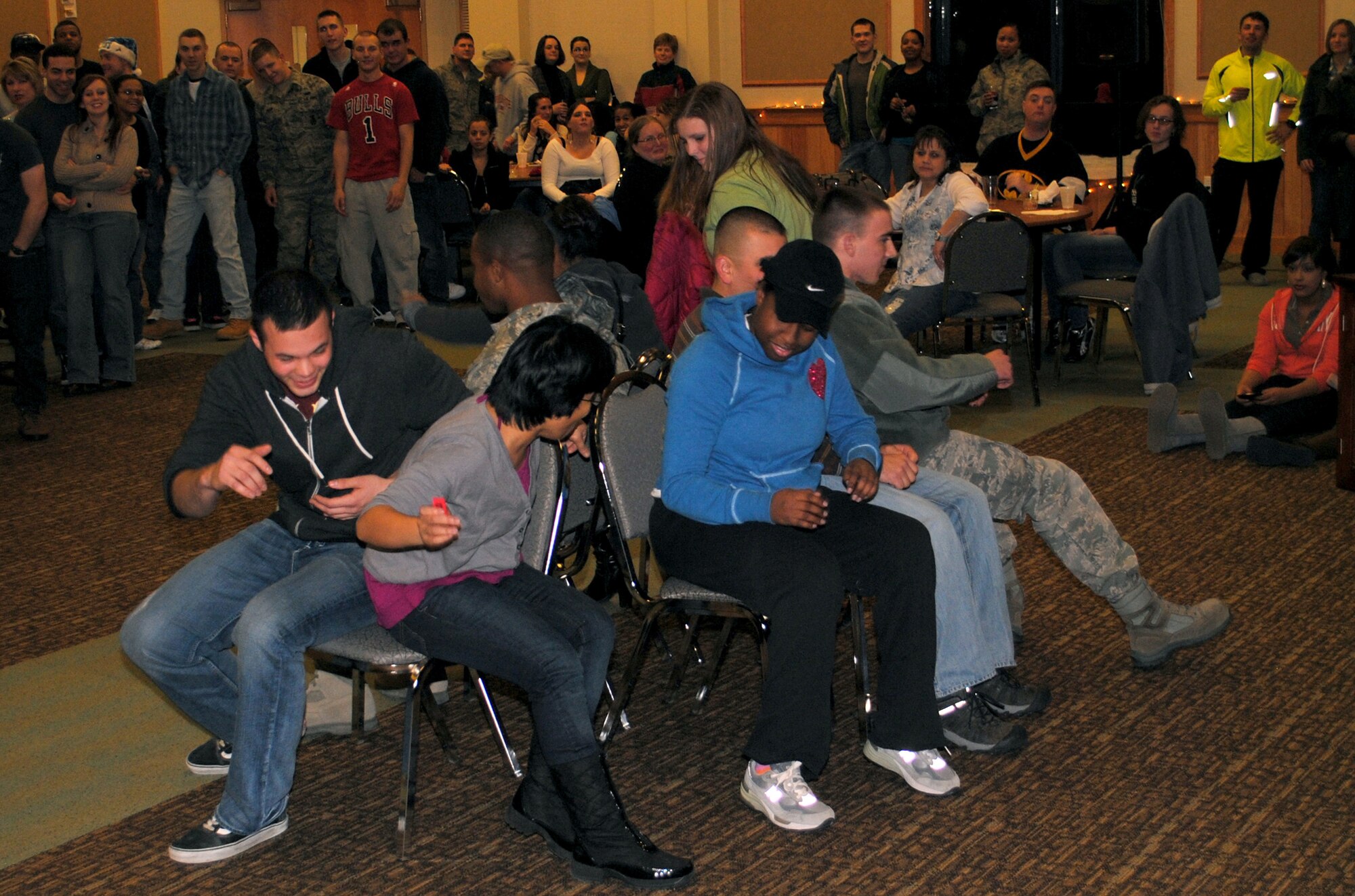 Several members of Team Malmstrom participate in a competitive game of musical chairs during the wrap-up party Dec. 15. The participants had their names drawn from a bucket to play the game for a chance to win a prize. 